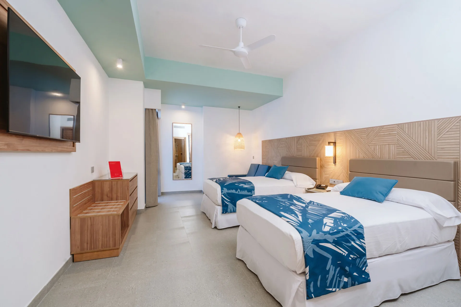 Guest room with two beds and wall-mounted TV at Hotel Riu Latino.
