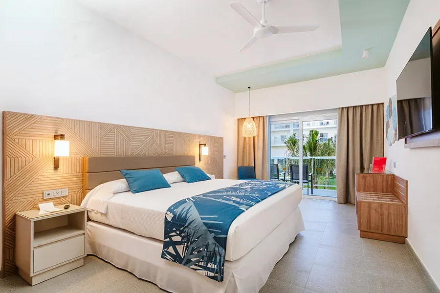Swim-up guest room with king bed and balcony view at Hotel Riu Latino.
