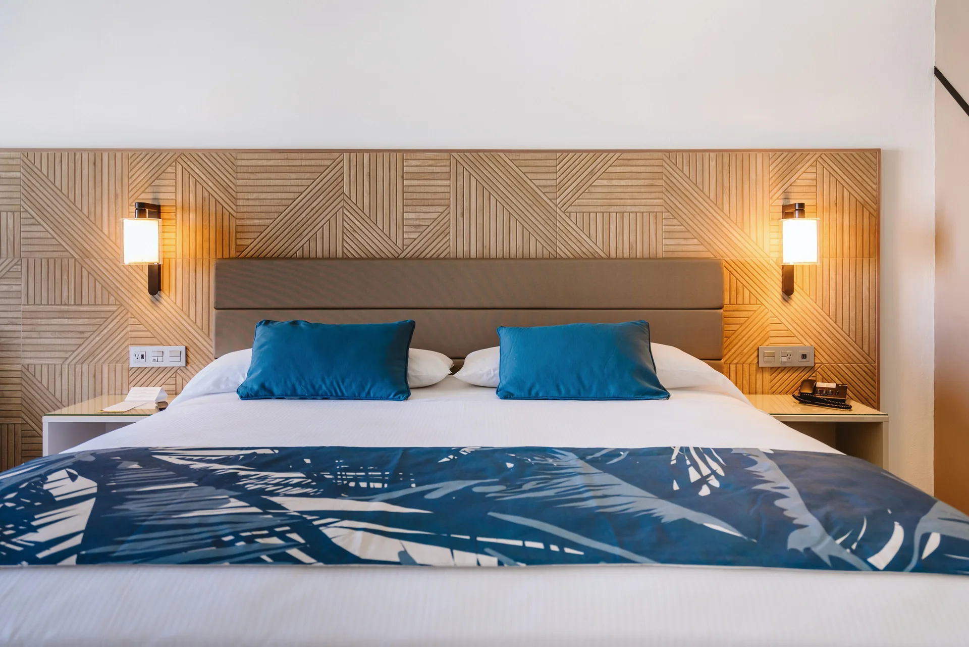 King bed with lit bedside lamps in an Ocean View Standard Room at Hotel Riu Latino.