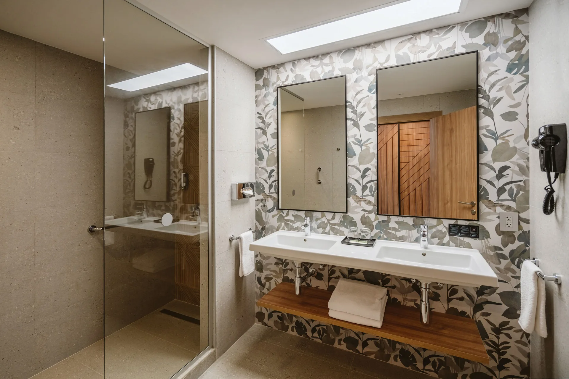Standard Room bathroom with double sinks and glass shower at Hotel Riu Latino.