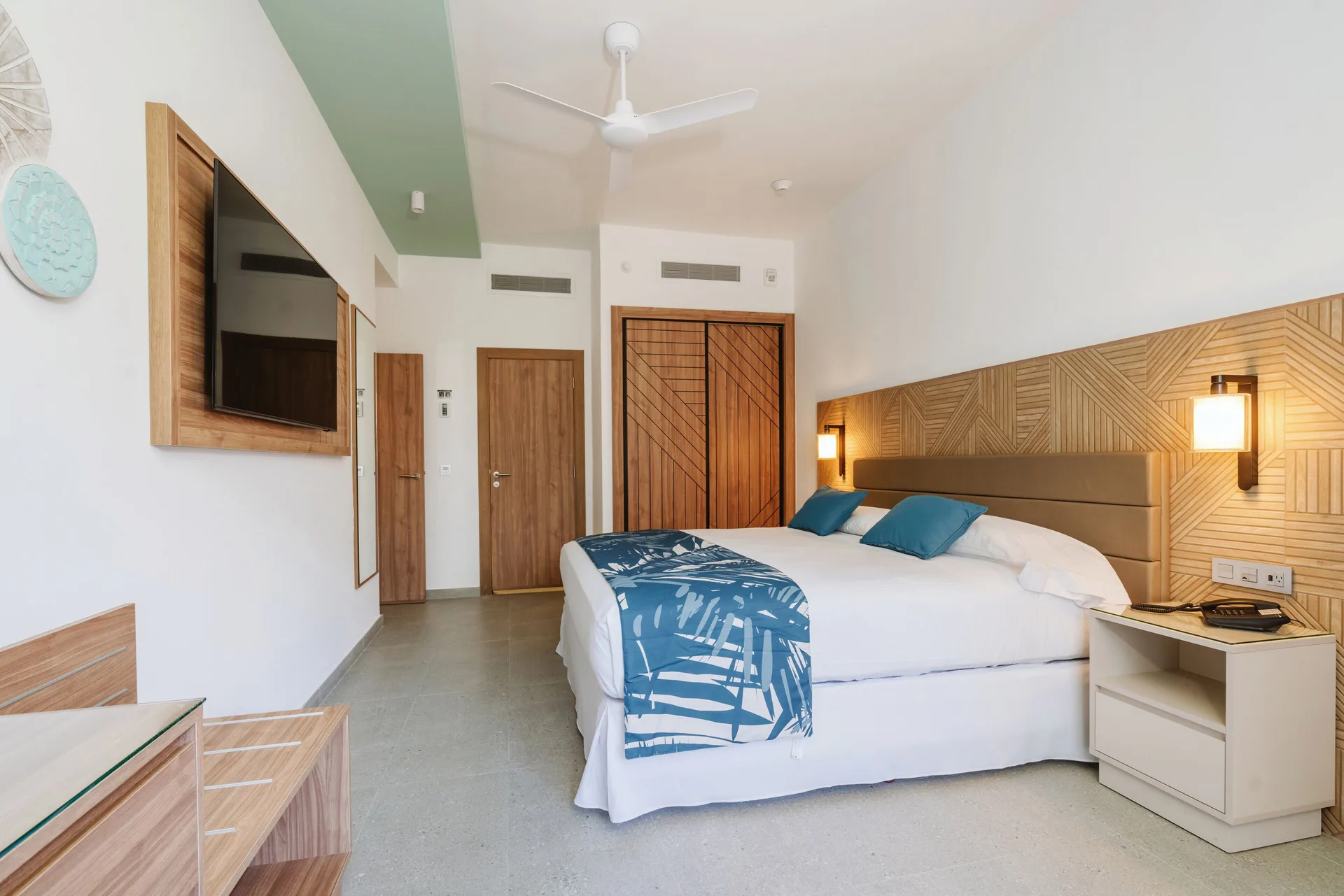 Standard Room with king bed, wall-mounted TV, and wood doors at Hotel Riu Latino.
