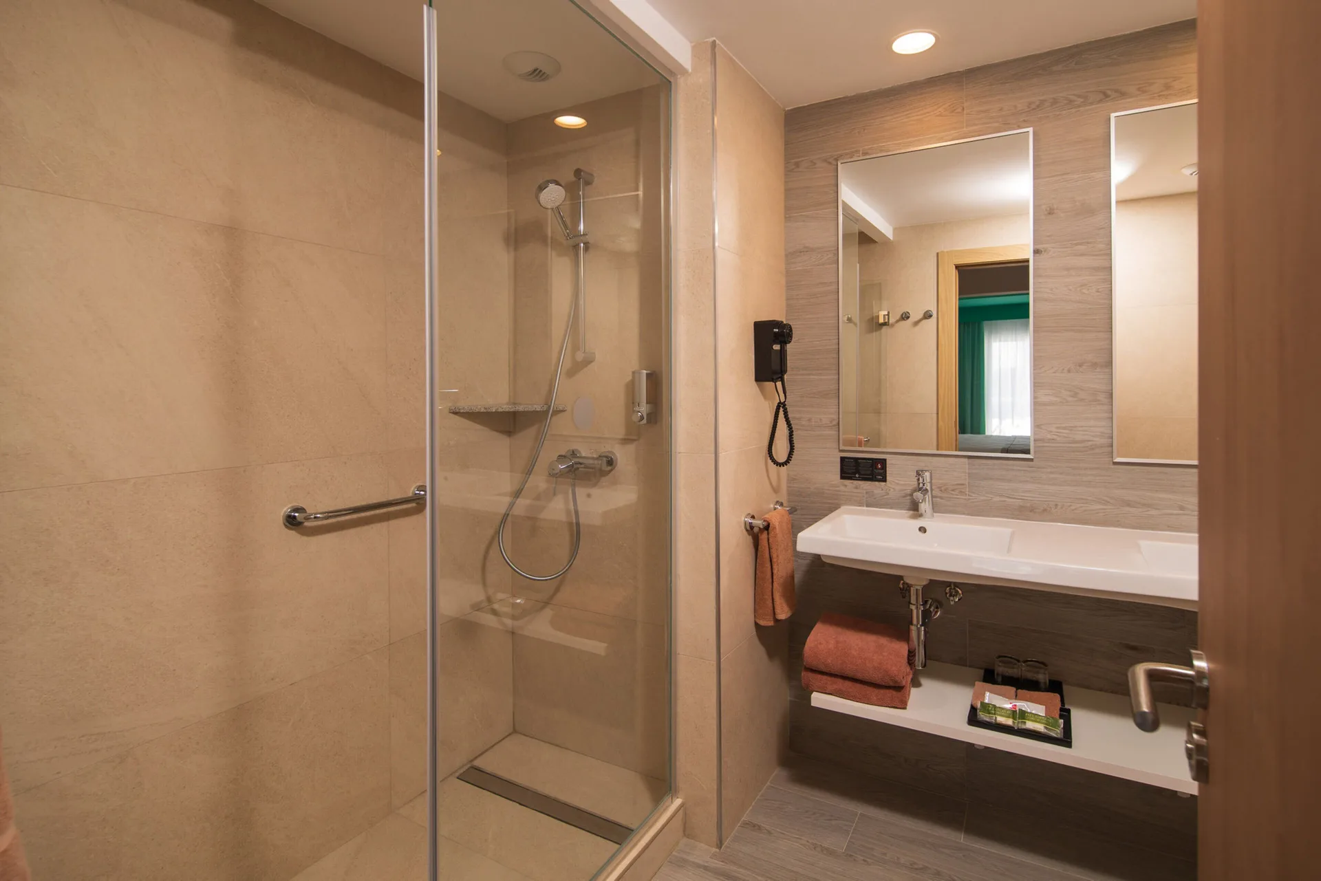 Ocean View room bathroom with glass shower, sink, mirrors, and towels at Hotel Riu Ocho Rios.