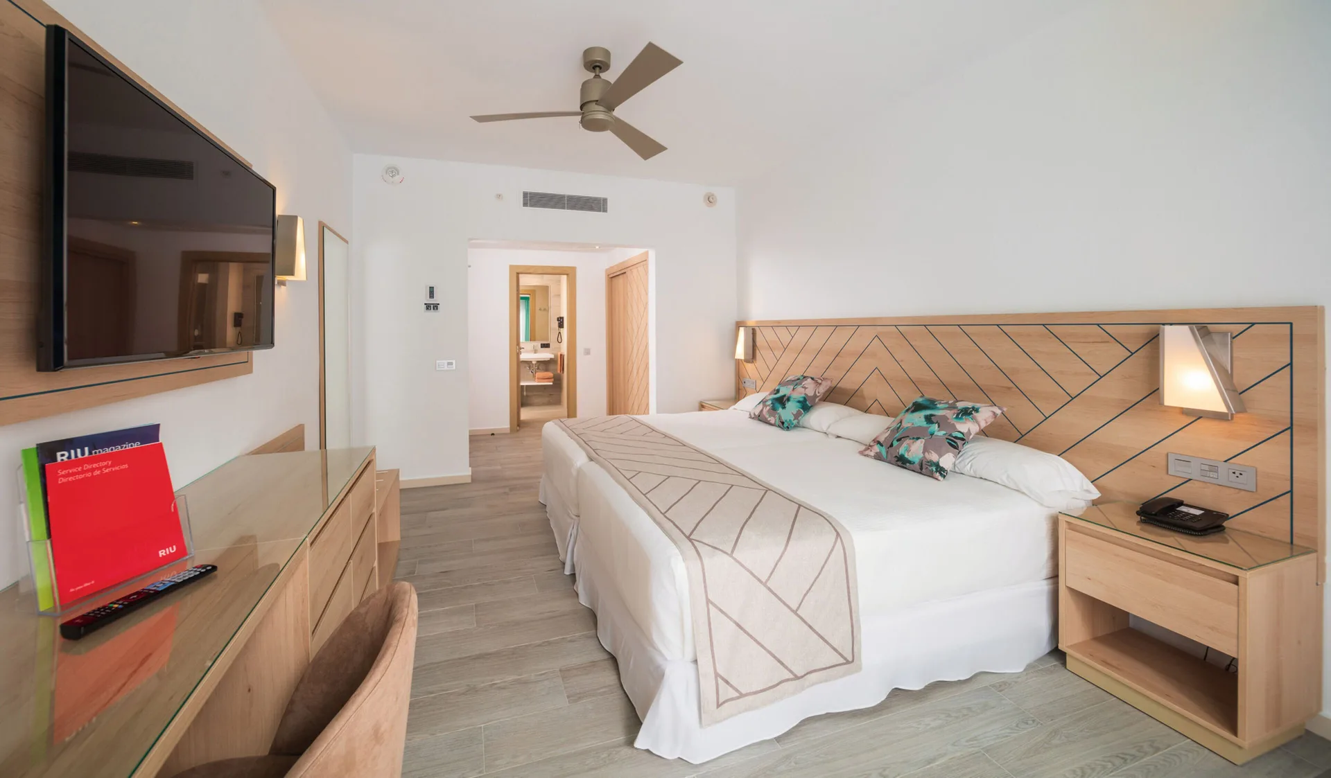 Ocean View room with a large bed, wall-mounted TV, and wood furniture at Hotel Riu Ocho Rios.