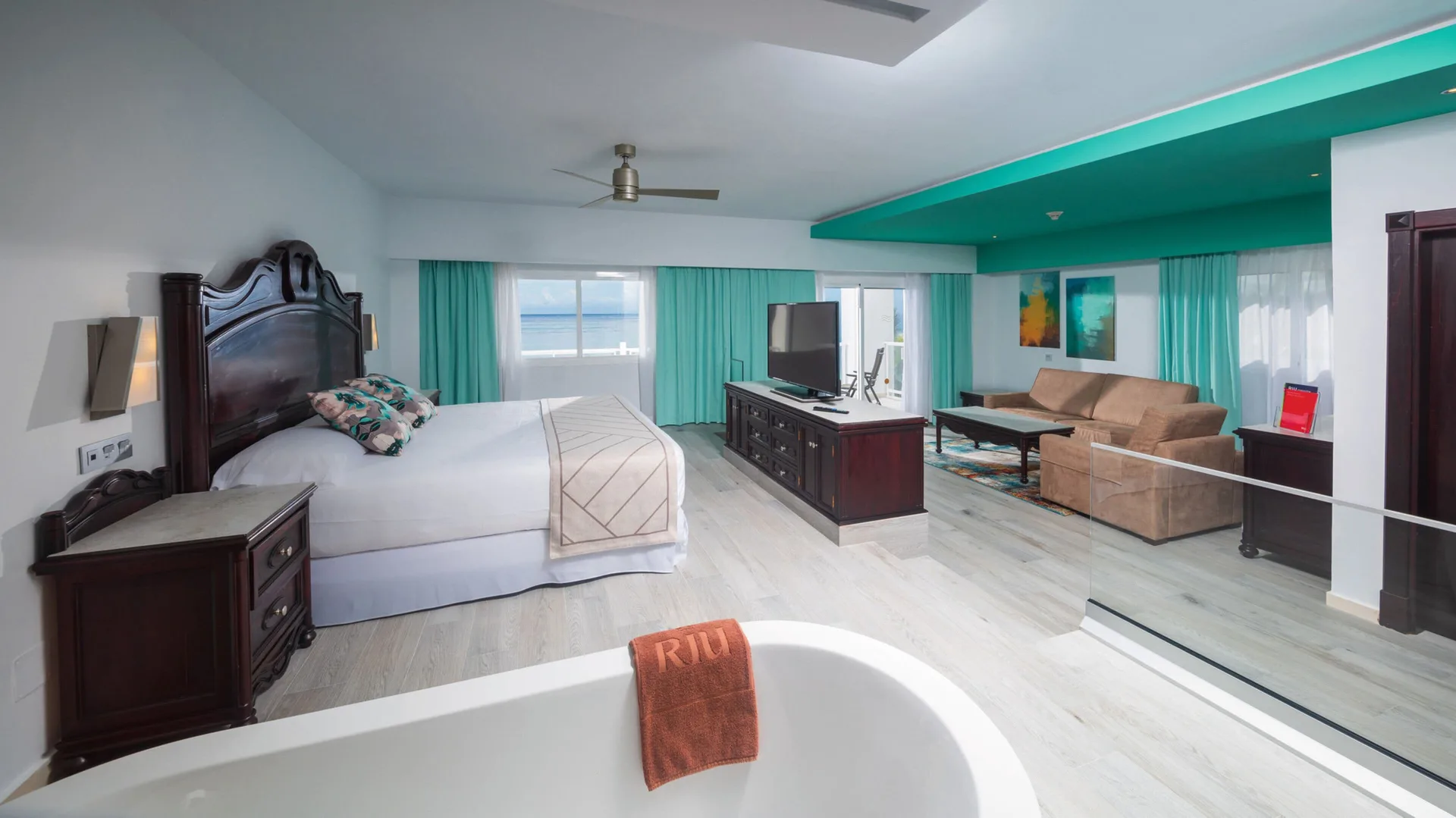 Ocean View Suite with king bed, bathtub, seating area and balcony doors at Hotel Riu Ocho Rios.