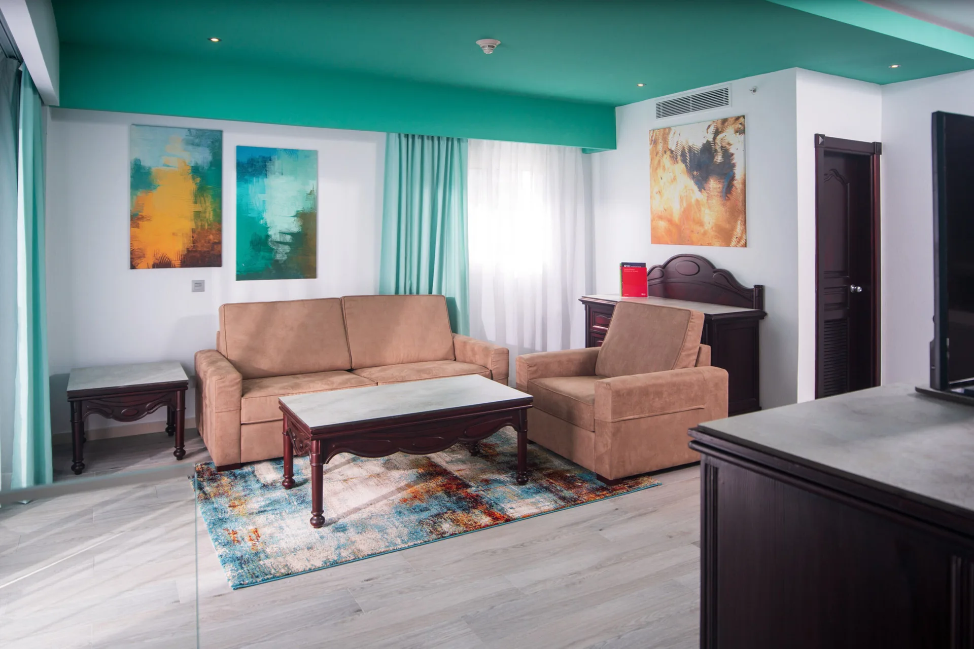 Ocean View Suite sitting area with sofa, armchair, tables and artwork at Hotel Riu Ocho Rios.