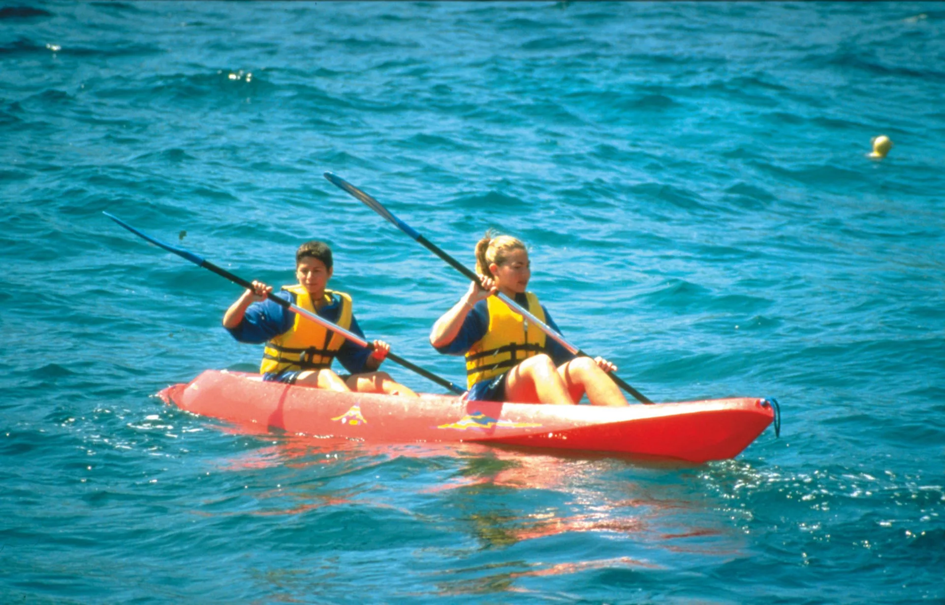 Two guests kayaking on blue ocean water at Hotel Riu Palace Costa Rica.