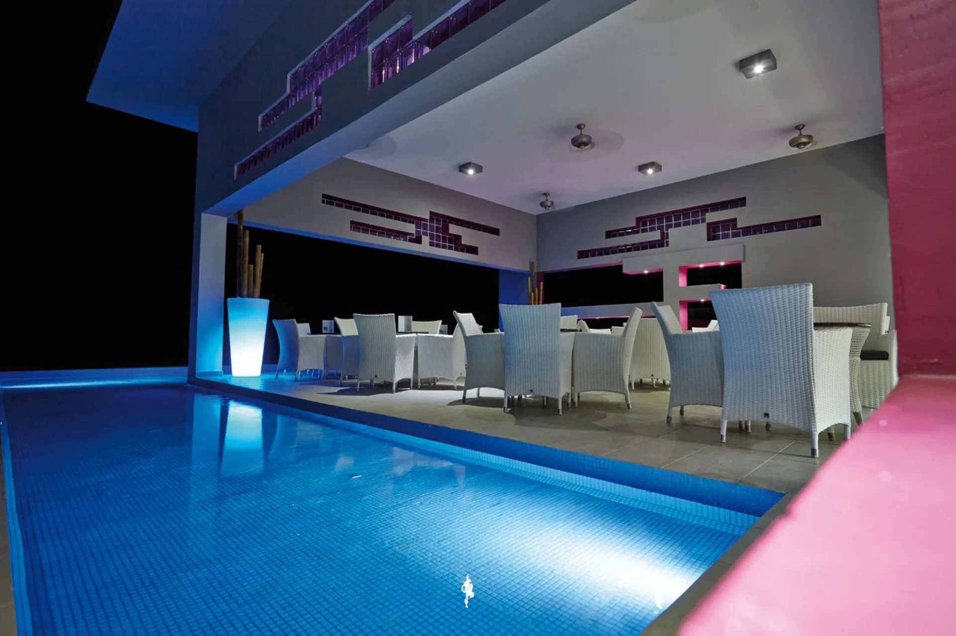 Nighttime poolside terrace with white chairs at Hotel Riu Palace Costa Rica.