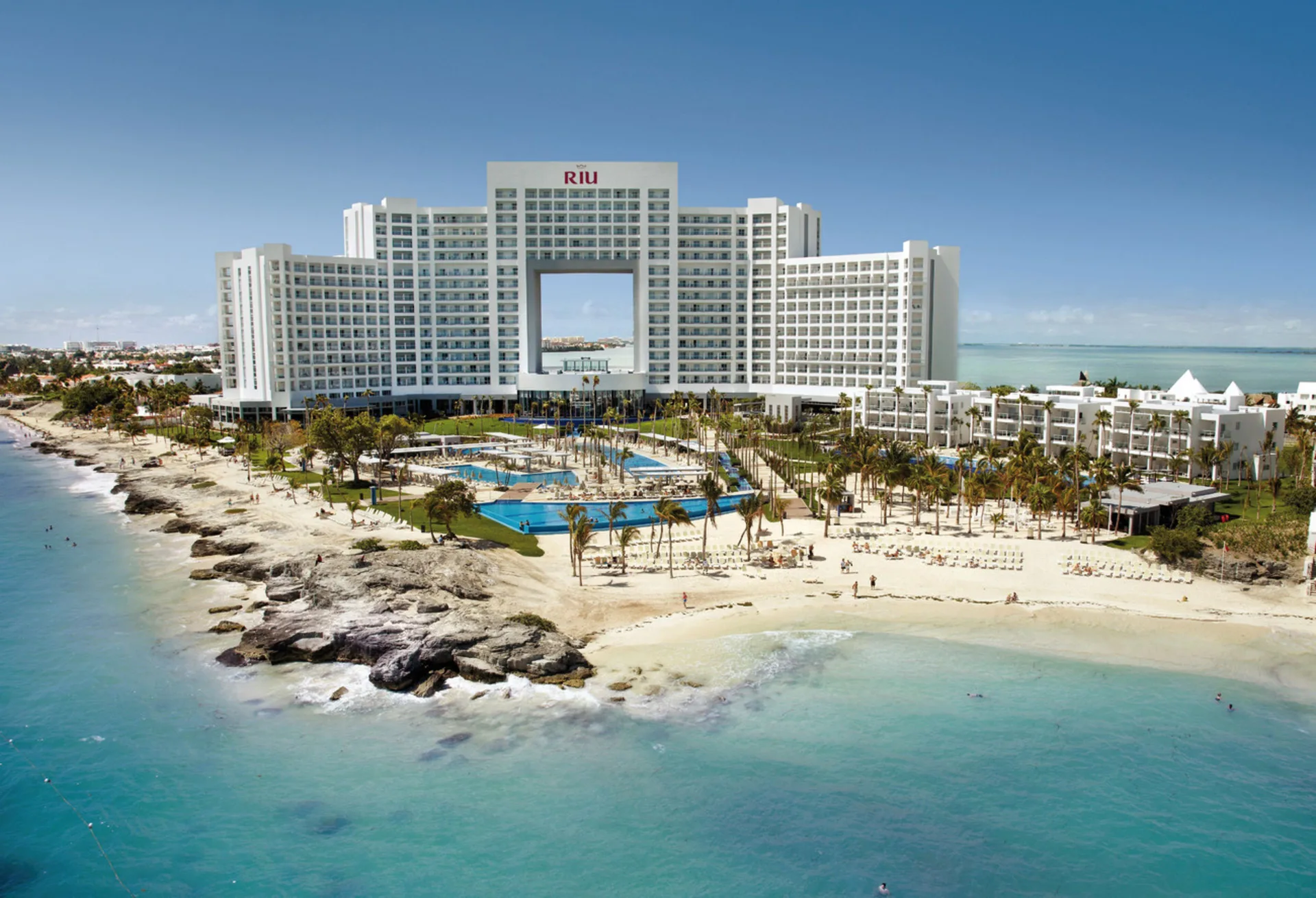 Aerial beach view of the main tower, pools and shoreline at Hotel Riu Palace Peninsula.