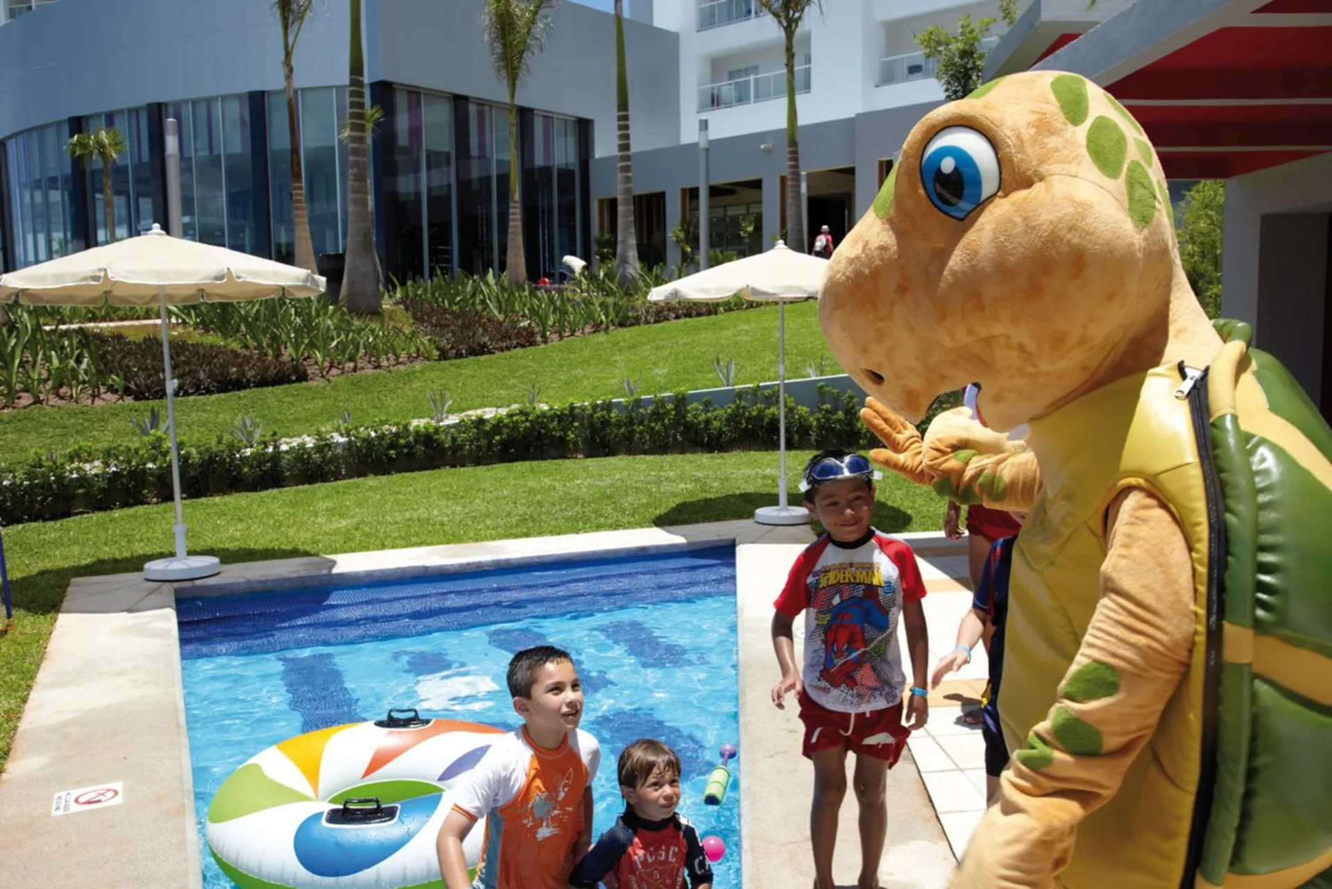 Children play near a small pool with a turtle mascot at Hotel Riu Palace Peninsula.