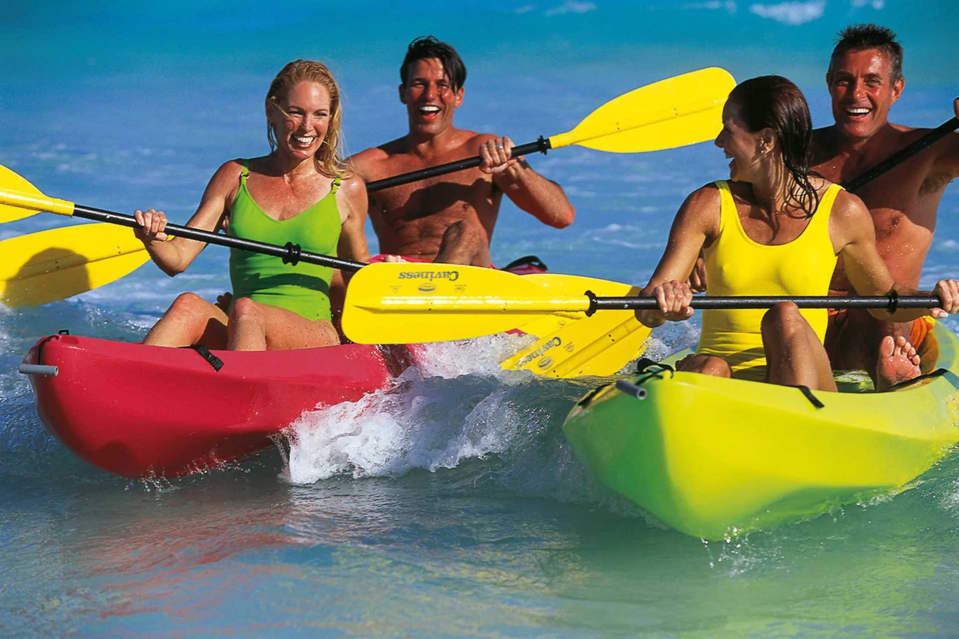 Guests paddling colorful kayaks in shallow blue water at Hotel Riu Palace Peninsula.
