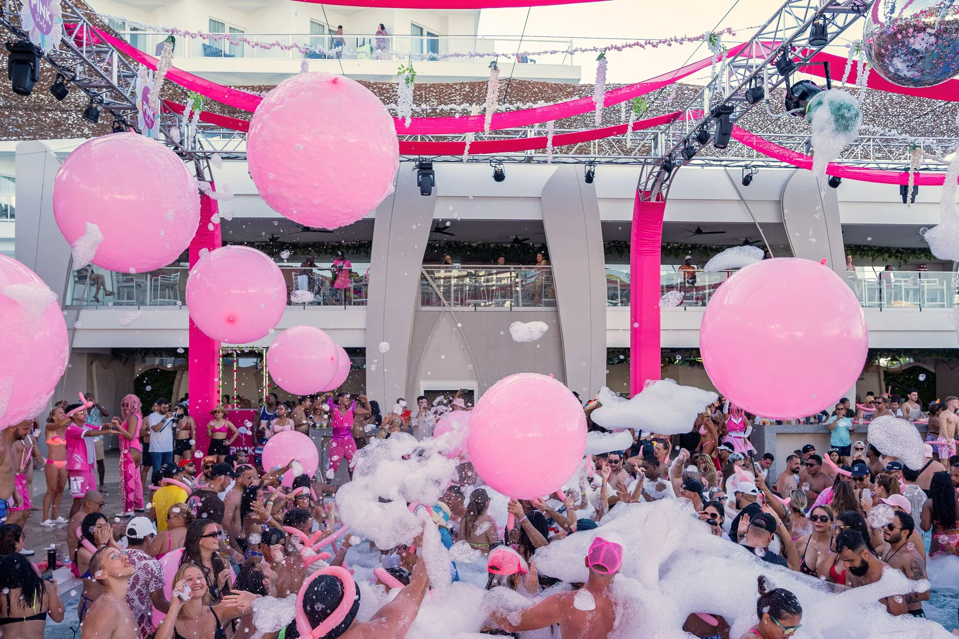 Large pink balloons and foam fill a pool party at Hotel Riu Palace Peninsula.
