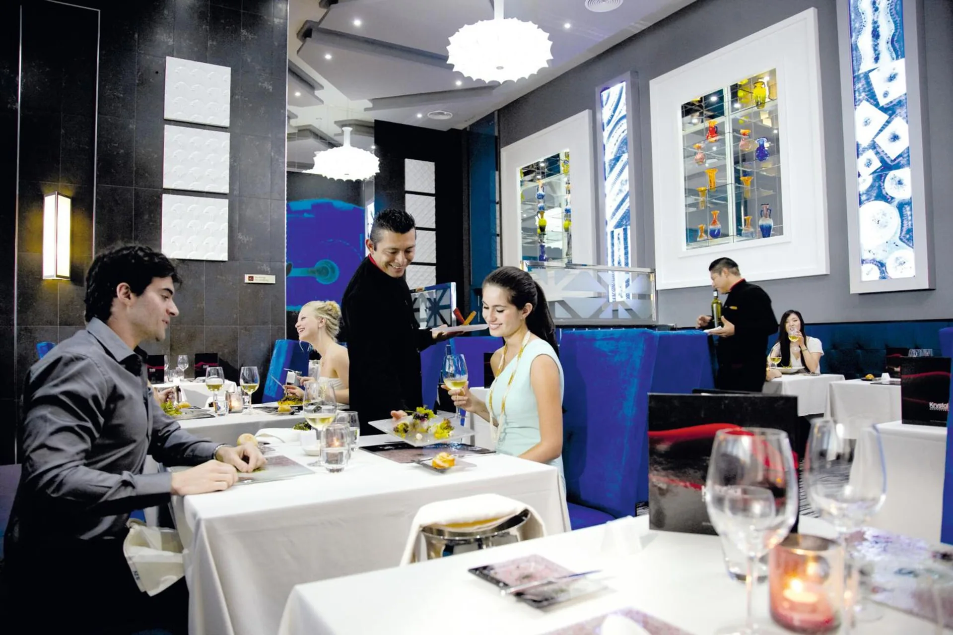 Krystal dining room with blue chairs and white tablecloths at Hotel Riu Palace Peninsula.