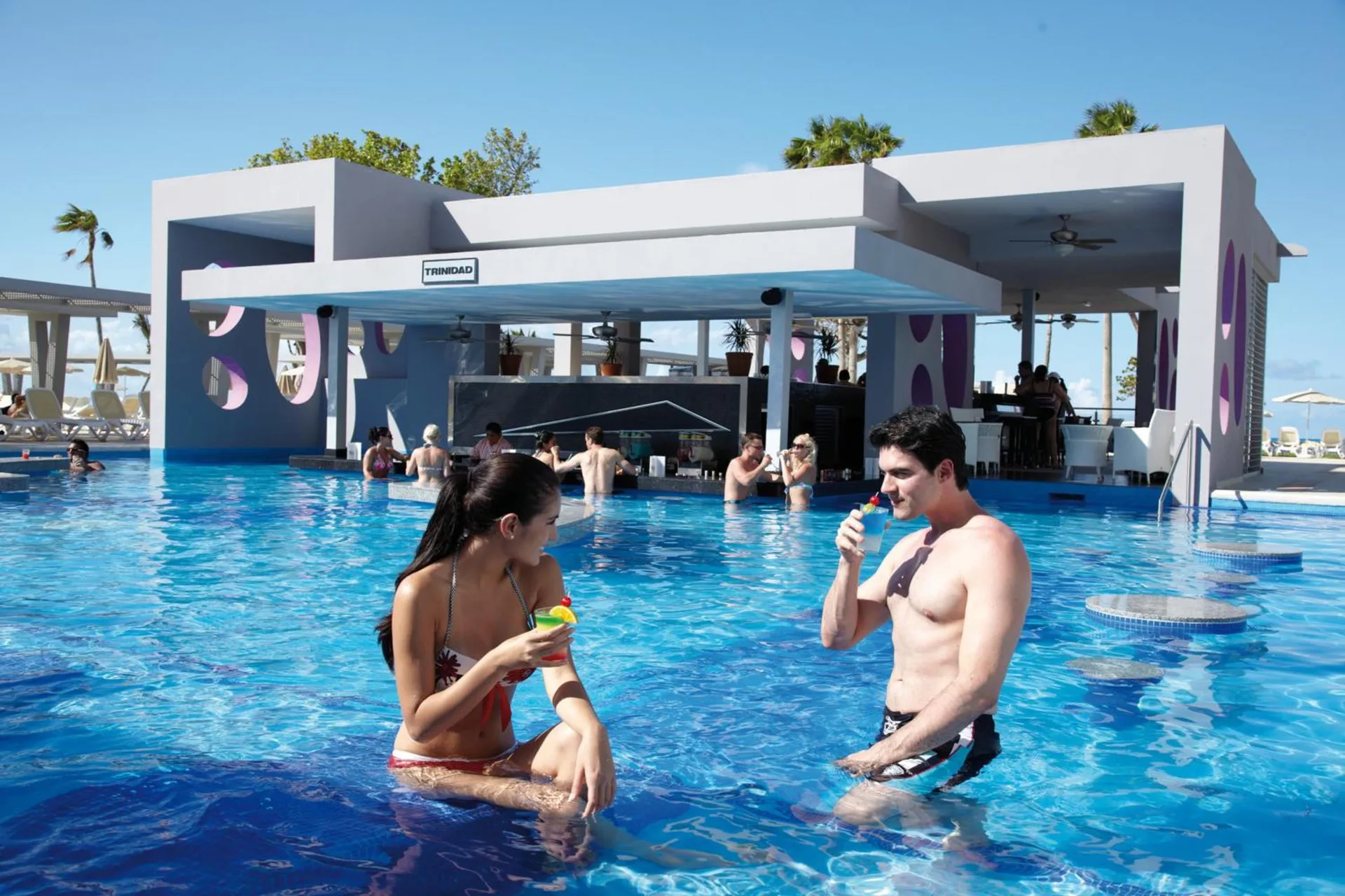 Swim-up pool bar with guests in the water at Hotel Riu Palace Peninsula.