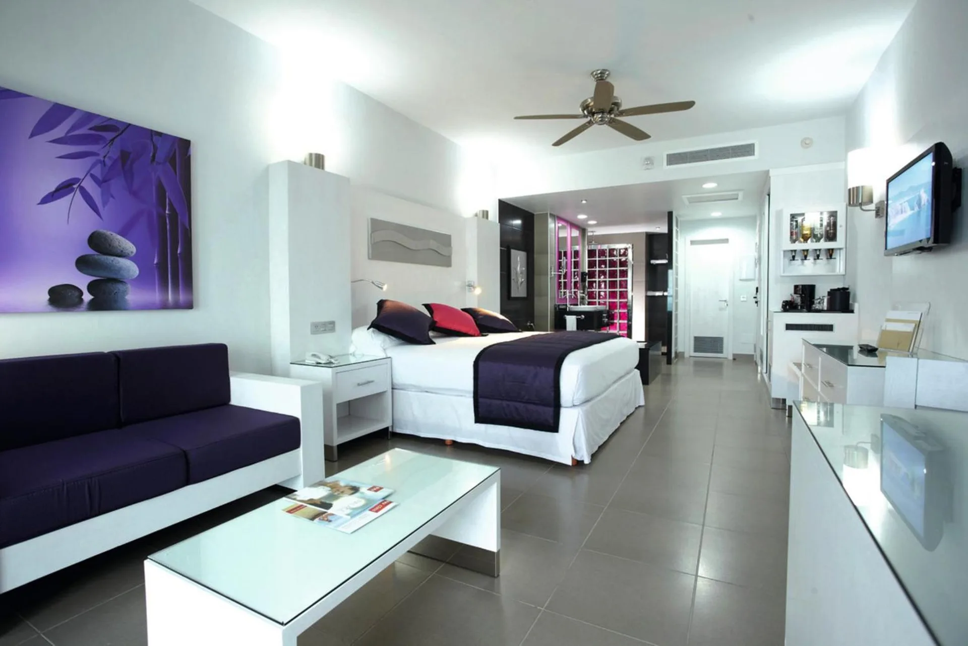 Junior Suite with king bed and purple sofa at Hotel Riu Palace Peninsula