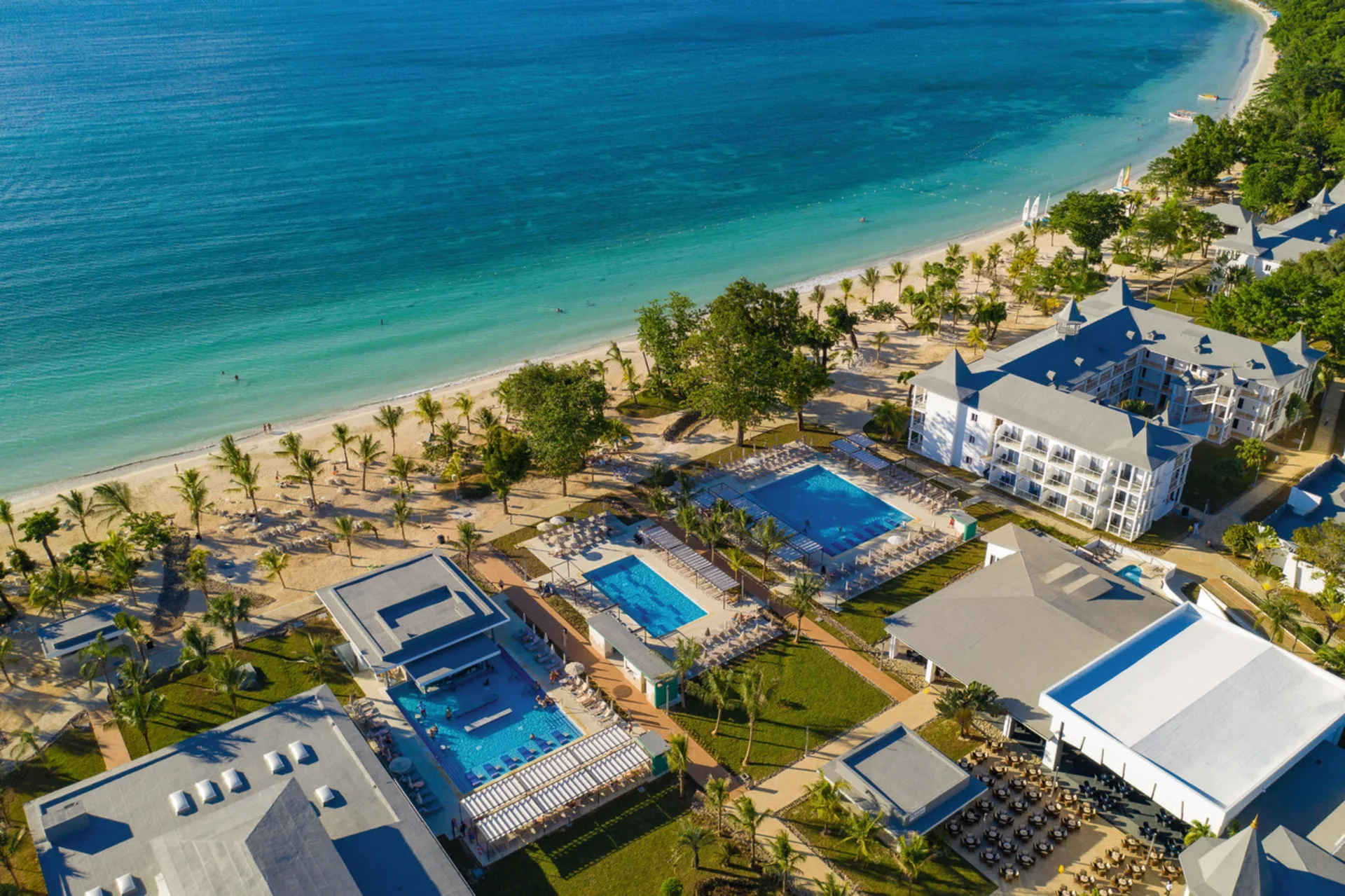 Aerial view of pools, buildings, and beach at Hotel Riu Palace Tropical Bay.