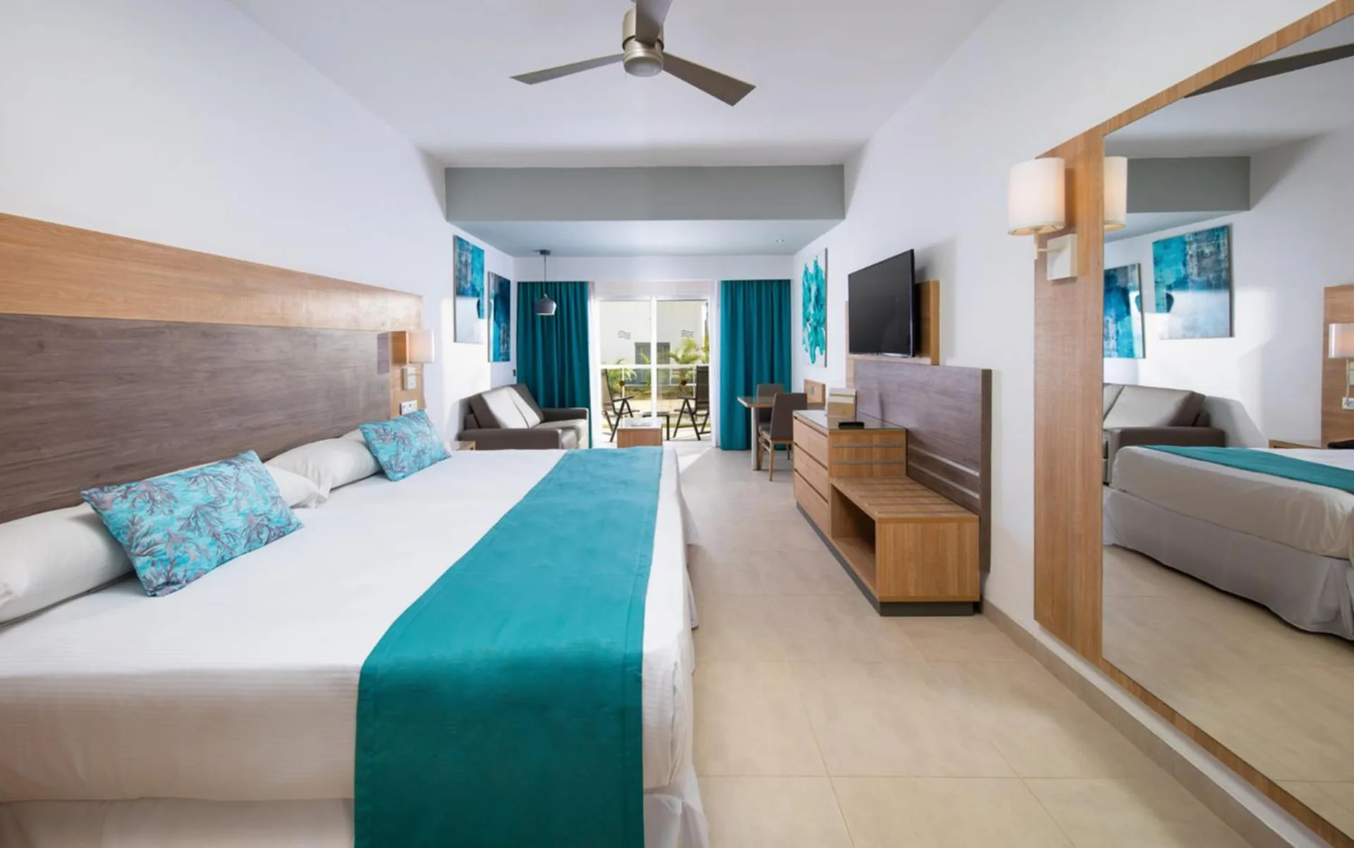 Junior Suite Garden View with balcony bed and seating at Hotel Riu Palace Tropical Bay.