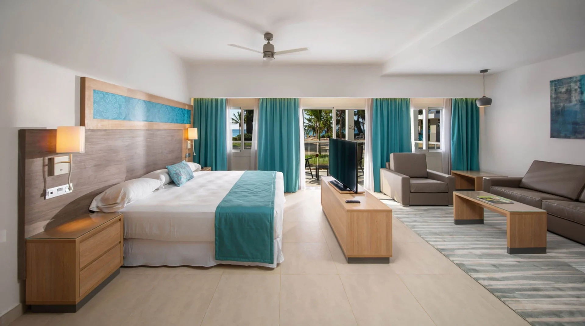 Ocean View suite with king bed and sitting area at Hotel Riu Palace Tropical Bay.