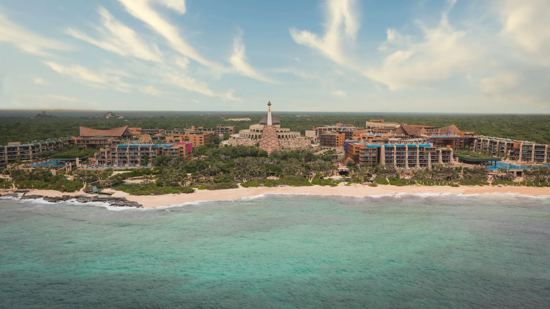 Aerial view of Hotel Xcaret Arte buildings along the beach and turquoise sea.