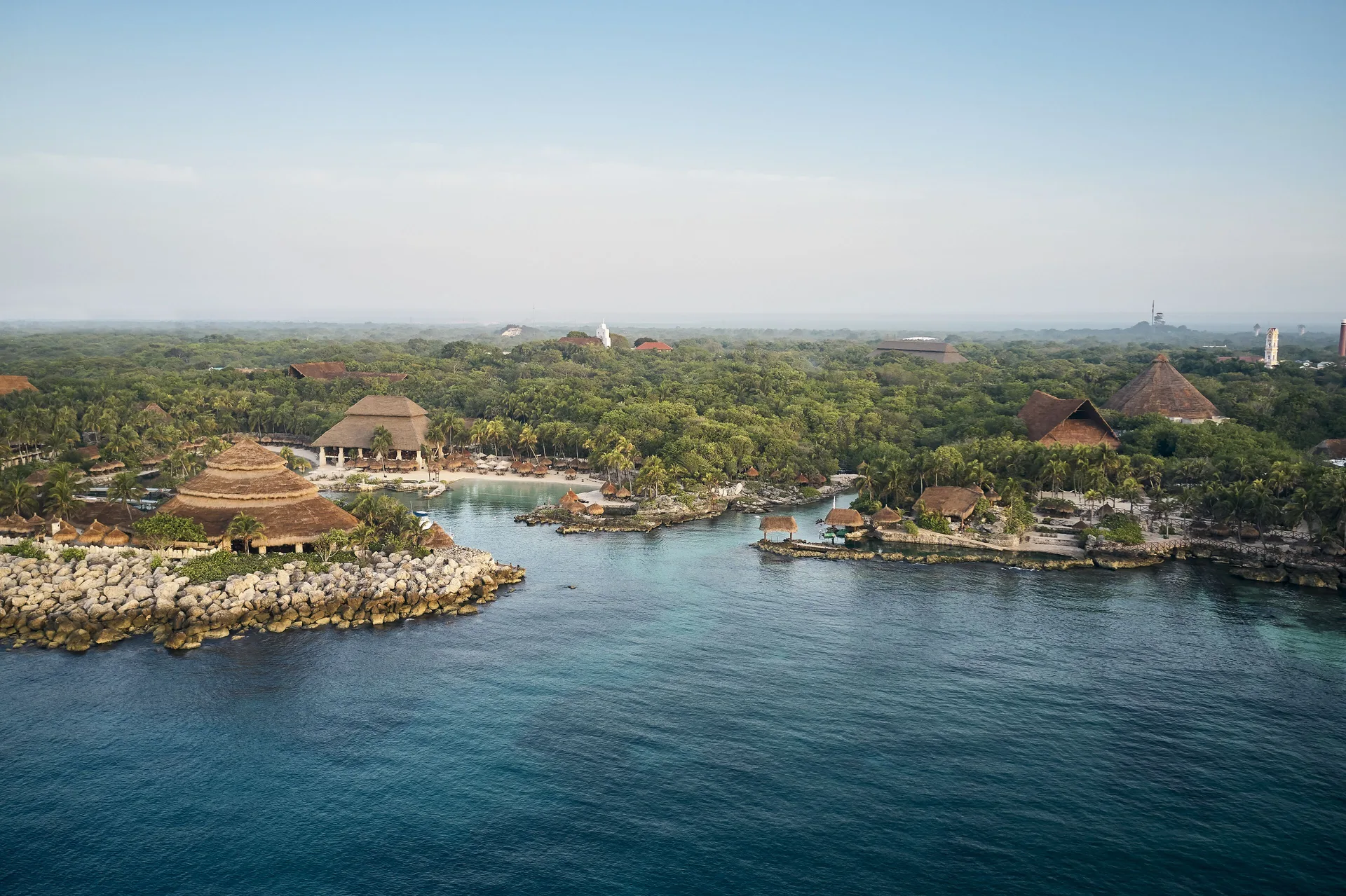 Aerial view of the coastline, coves, and thatched roofs at Hotel Xcaret Arte.