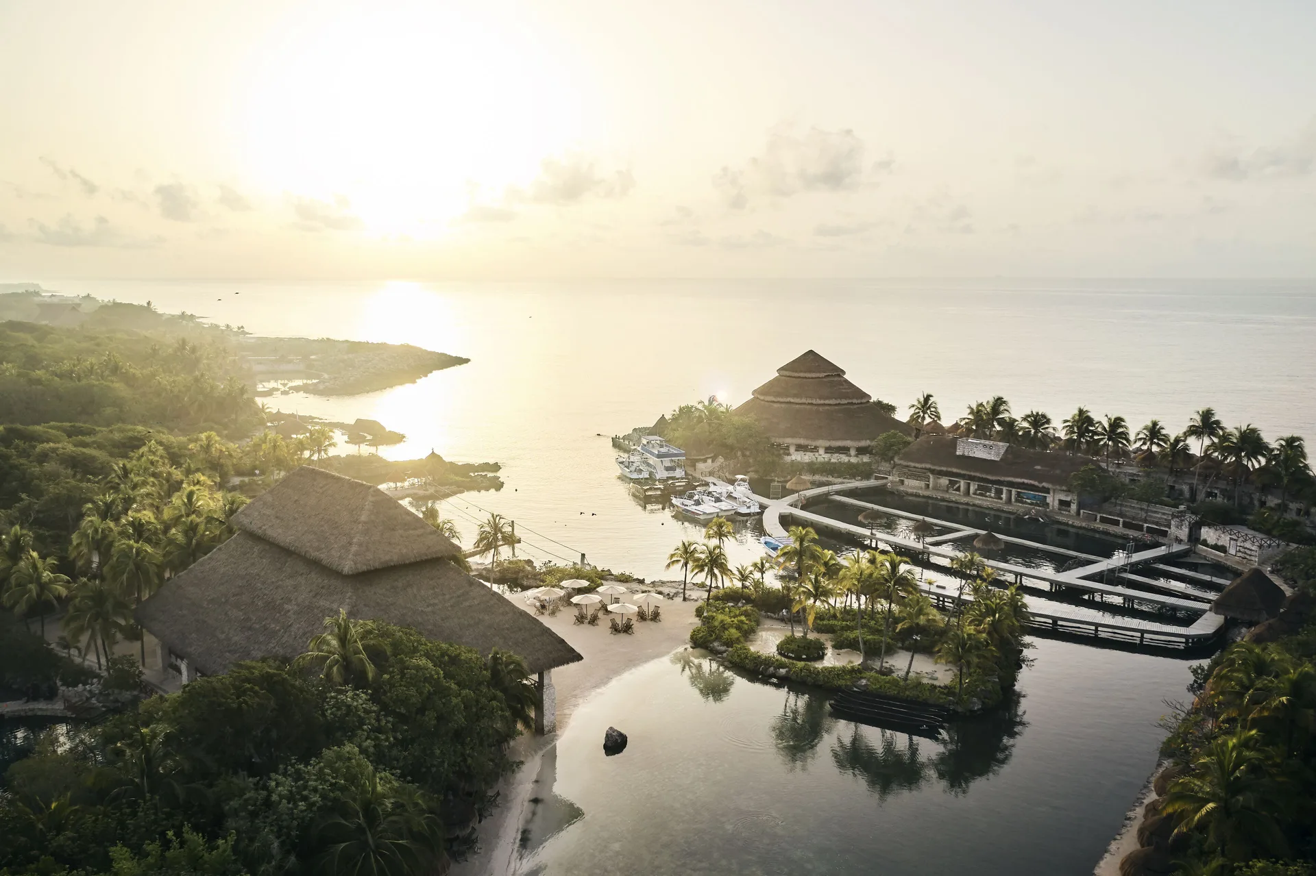 Aerial sunrise view of lagoons, palapa roofs, and ocean at Hotel Xcaret Arte.
