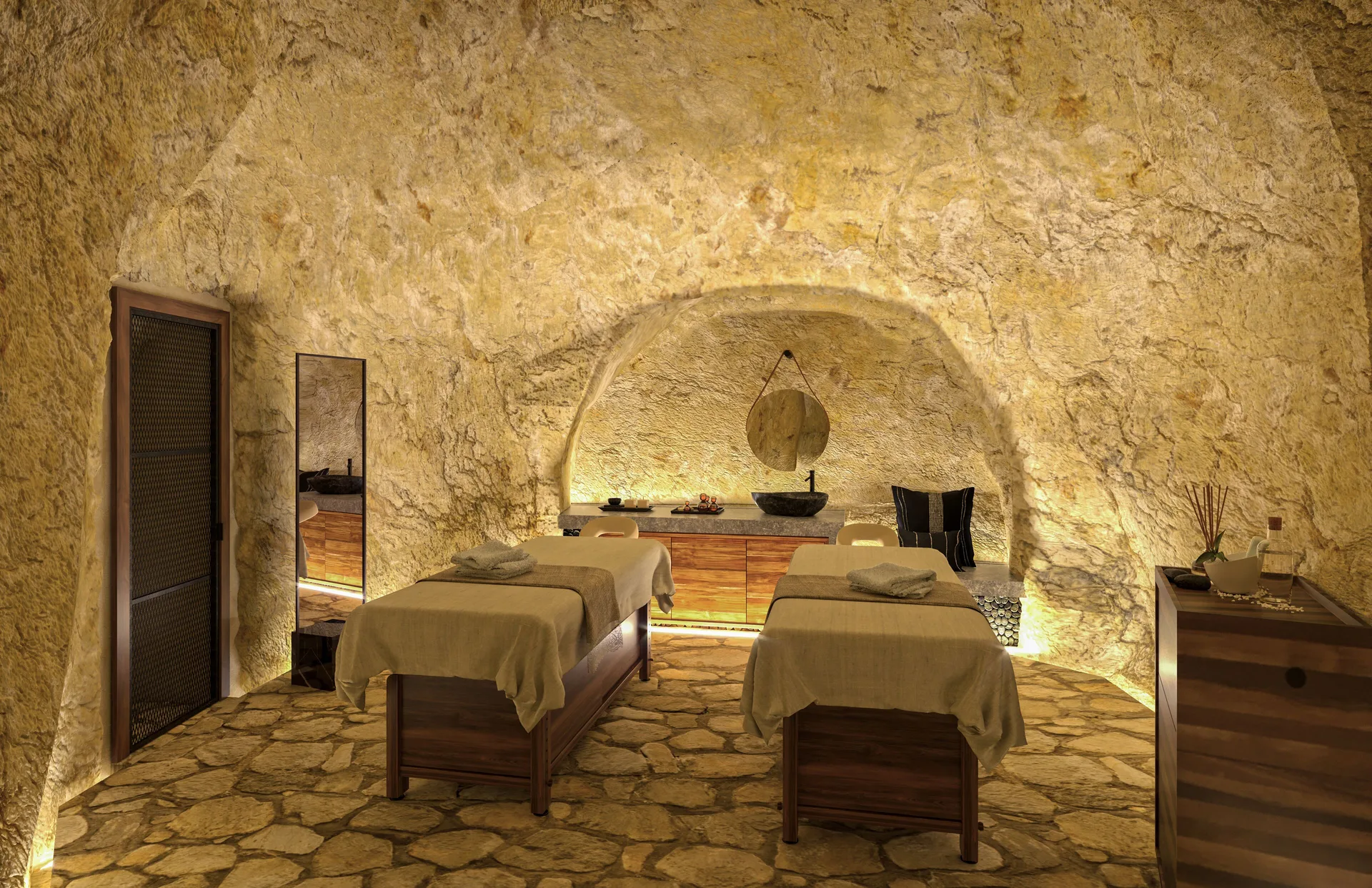 Spa treatment room with two massage tables in a stone cave setting at Hotel Xcaret Arte.
