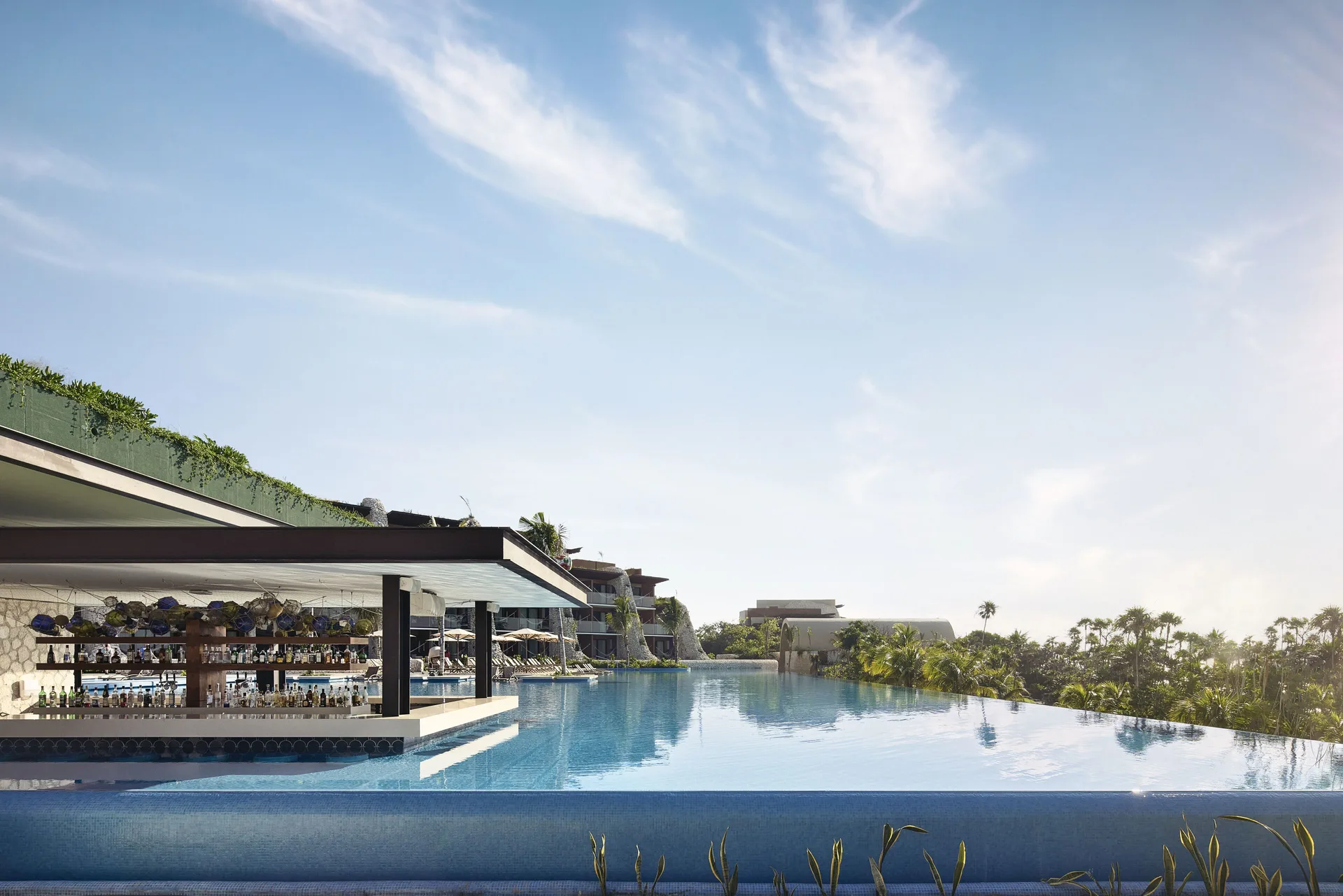 Infinity pool with a swim-up bar and treetop views at Hotel Xcaret Arte.