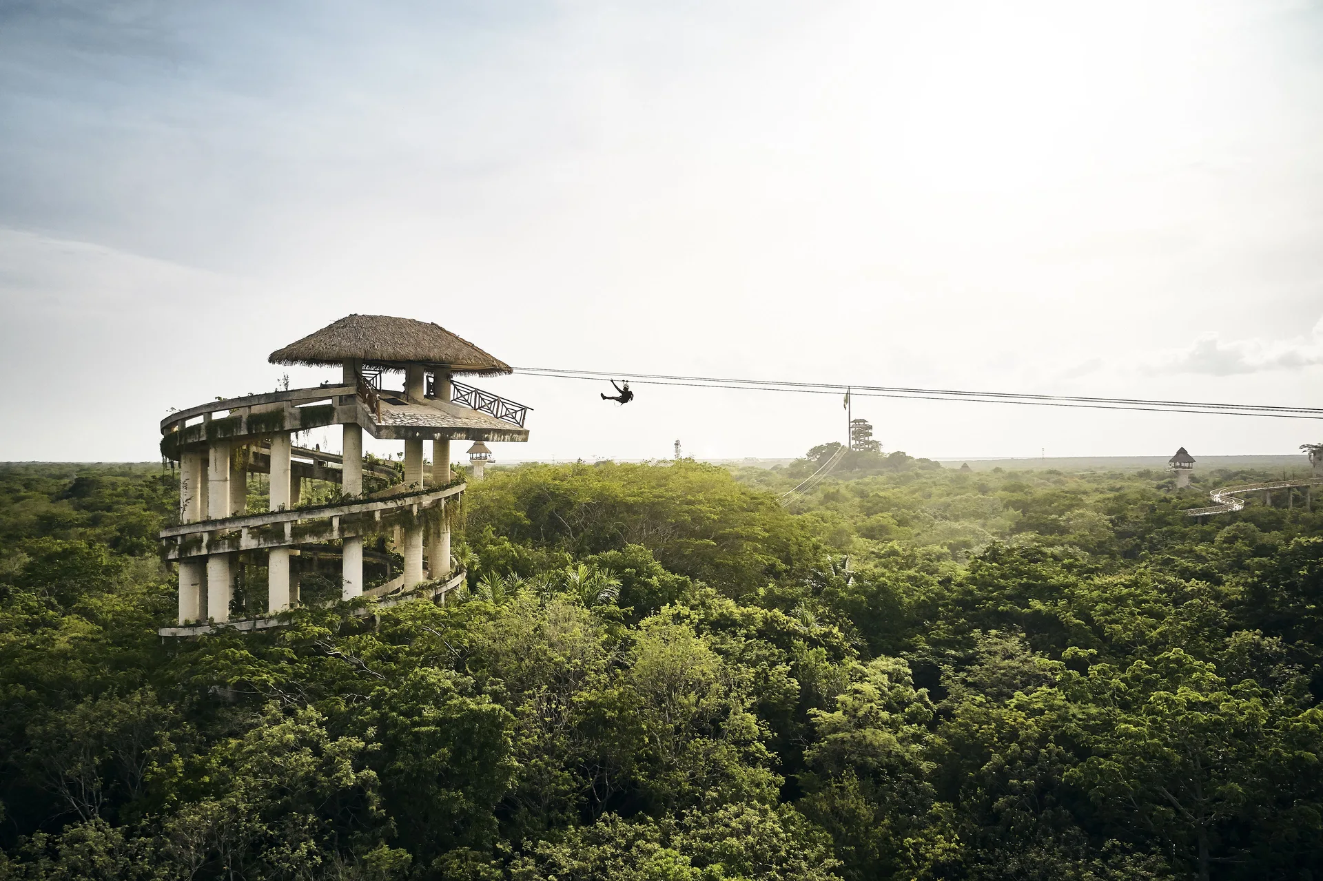 Zipline rider crossing above jungle near Hotel Xcaret Arte.
