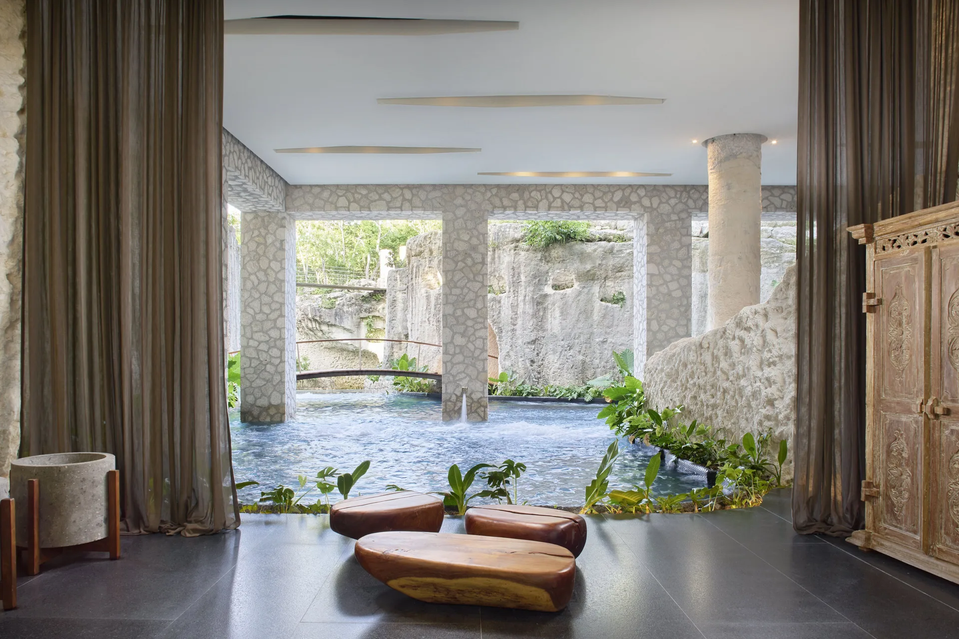 Lobby lounge with water feature and stone columns at Hotel Xcaret Arte.