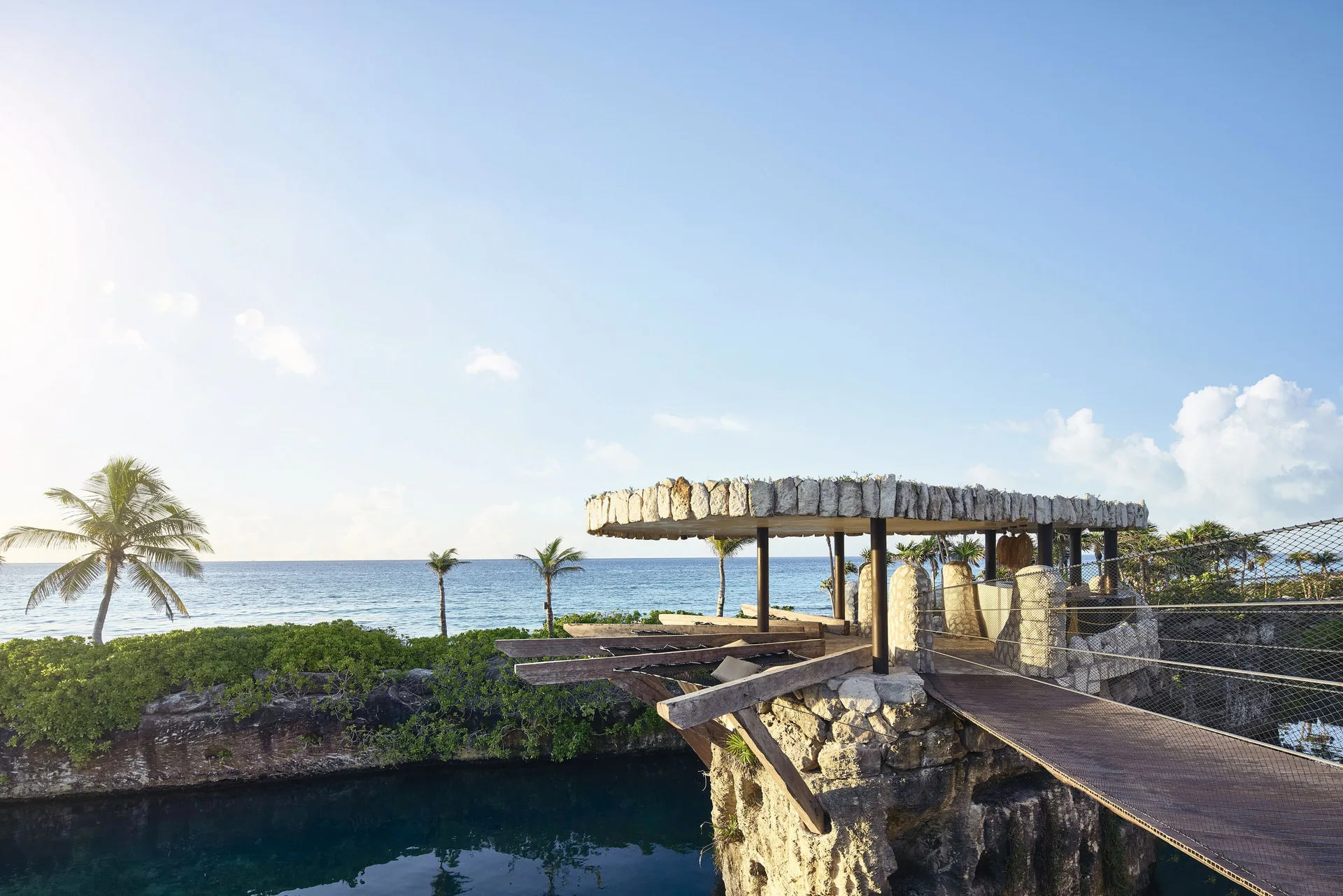Oceanfront wooden bridge and rocky pavilion at Hotel Xcaret Arte.
