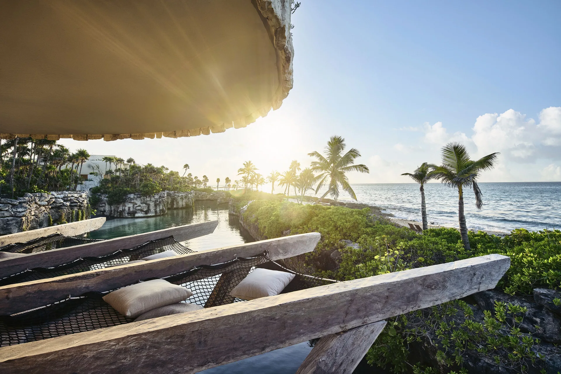 Net lounge deck overlooking palms and the ocean at Hotel Xcaret Arte.
