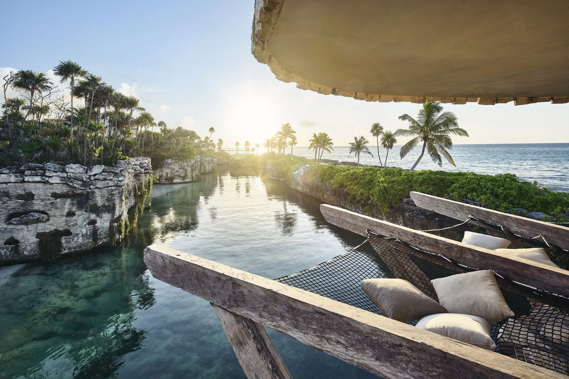 Overwater hammock deck beside a lagoon and ocean at Hotel Xcaret Arte.