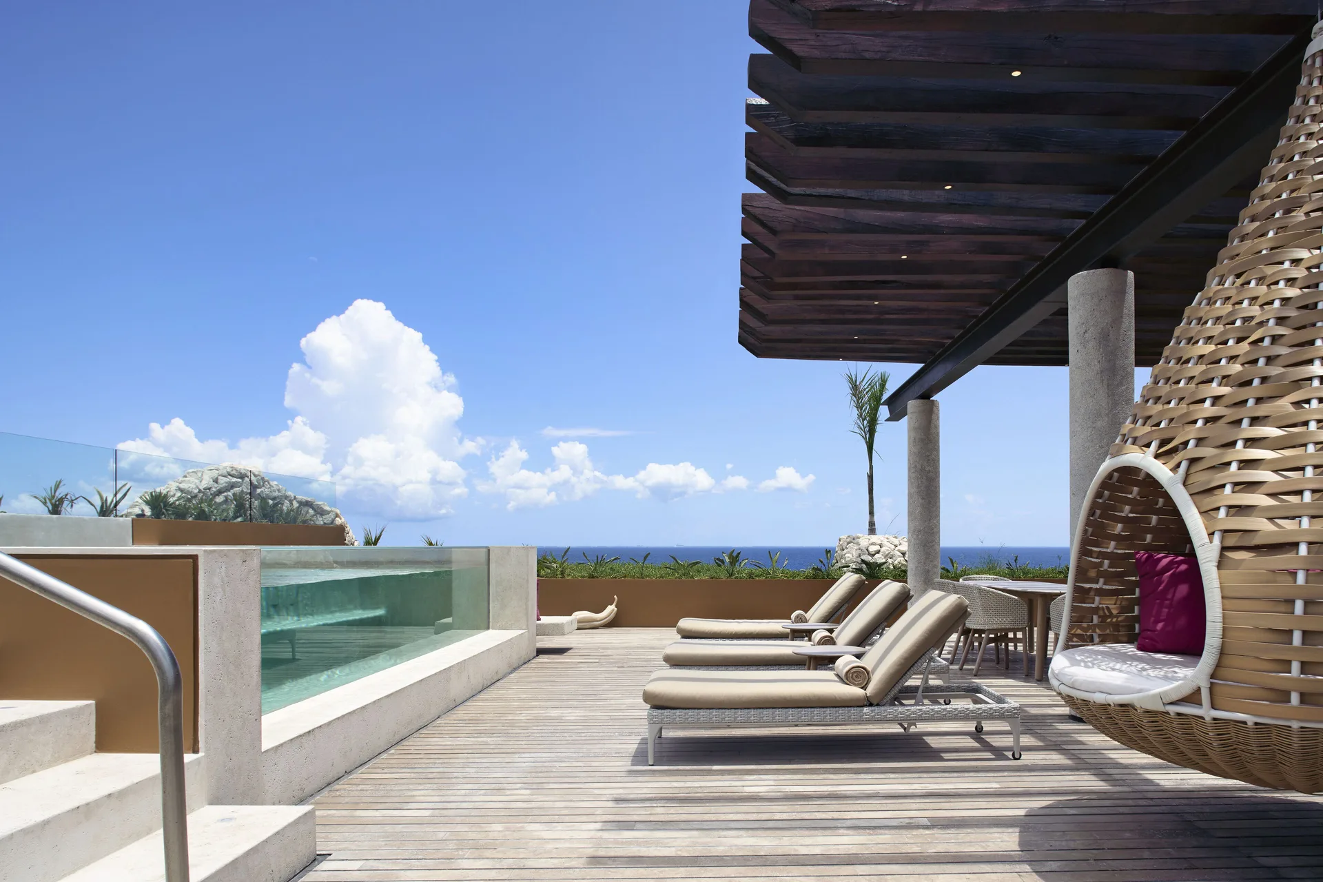 Rooftop pool deck with loungers and hanging chair at Hotel Xcaret Arte.