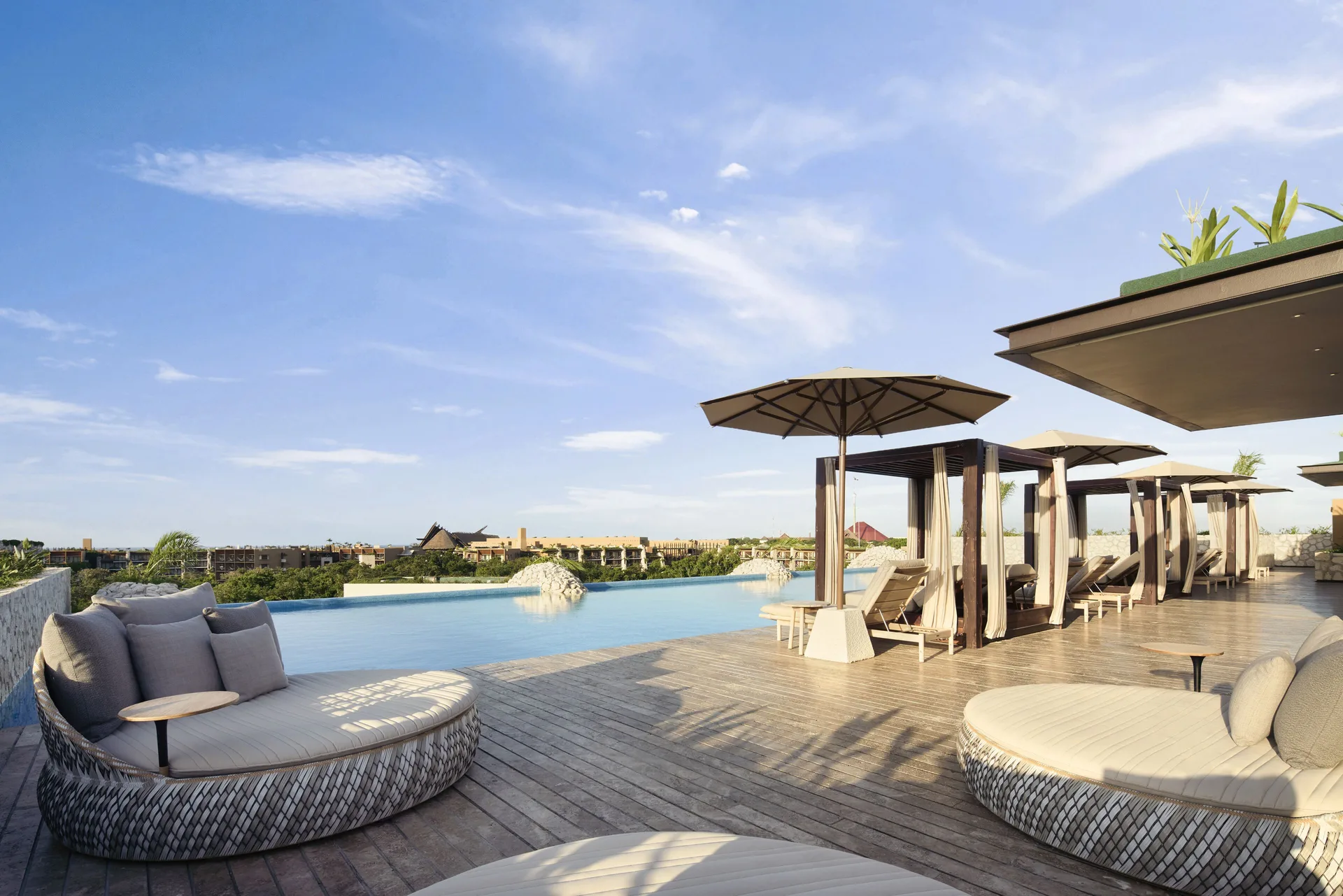 Rooftop pool terrace with round daybeds and cabanas at Hotel Xcaret Arte.