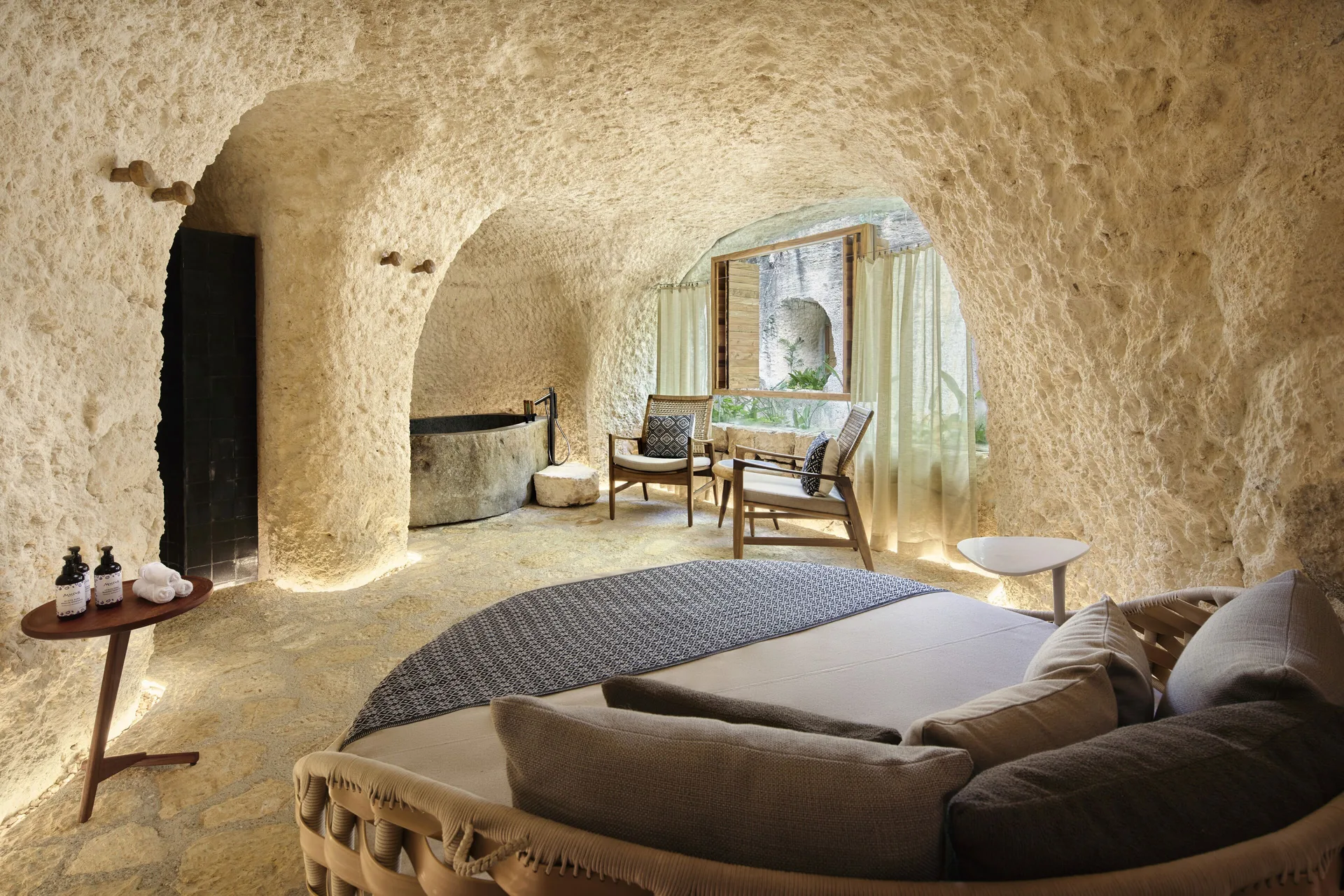 Spa lounge with curved stone walls and cushioned seating at Hotel Xcaret Arte.