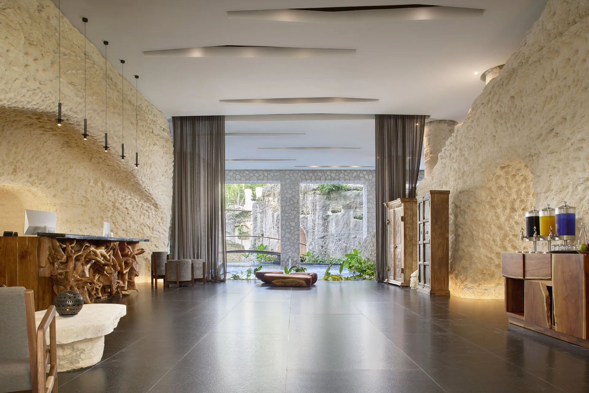 Stone-walled lobby with carved wood reception desk at Hotel Xcaret Arte.