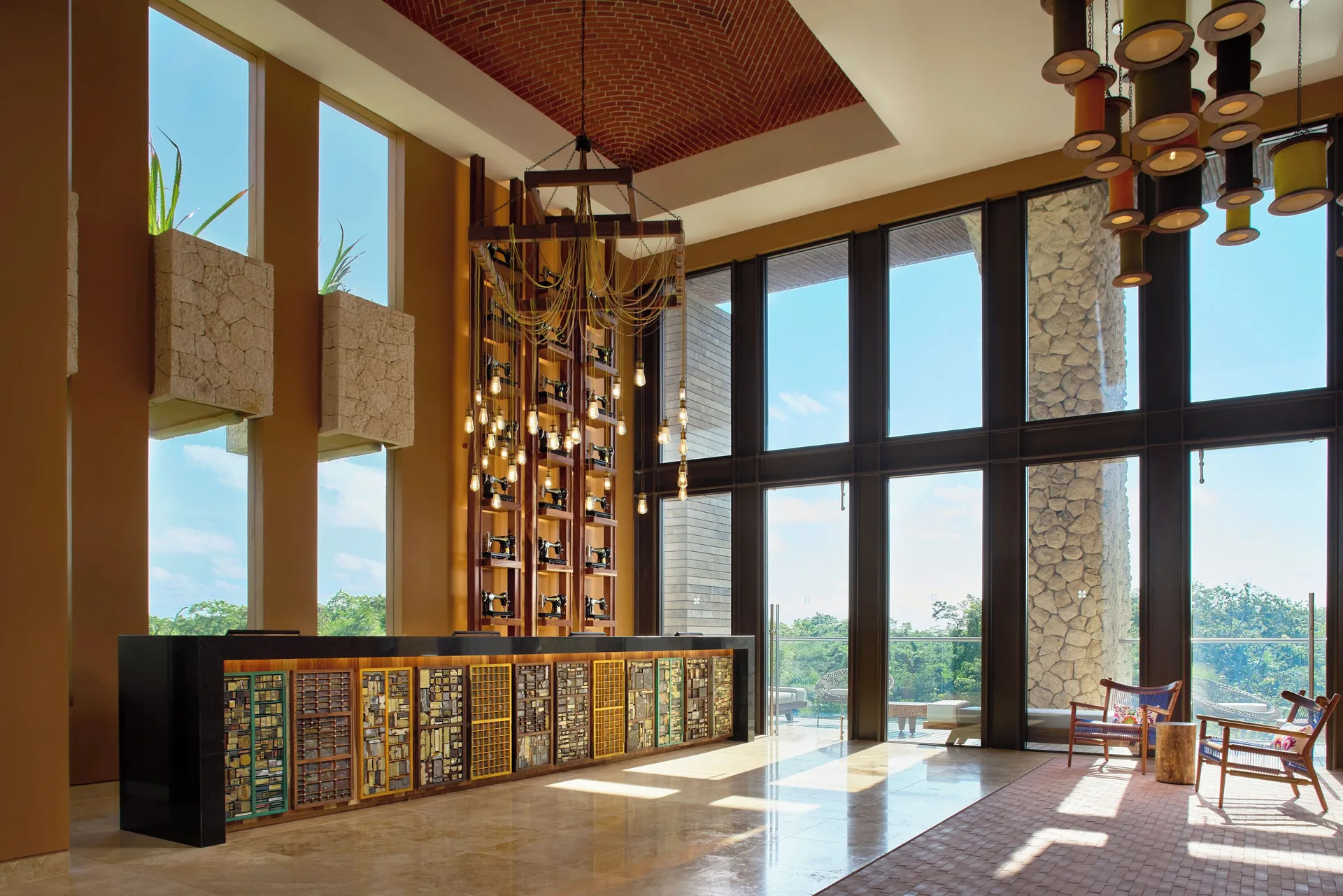 Sunlit lobby lounge with a decorative reception desk at Hotel Xcaret Arte.