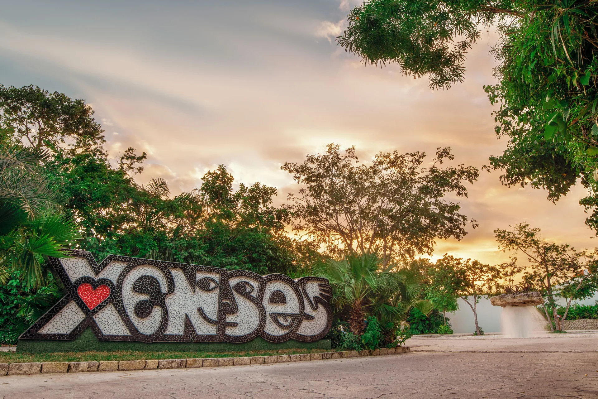Large Xcaret entrance sign among tropical trees at Hotel Xcaret Arte.