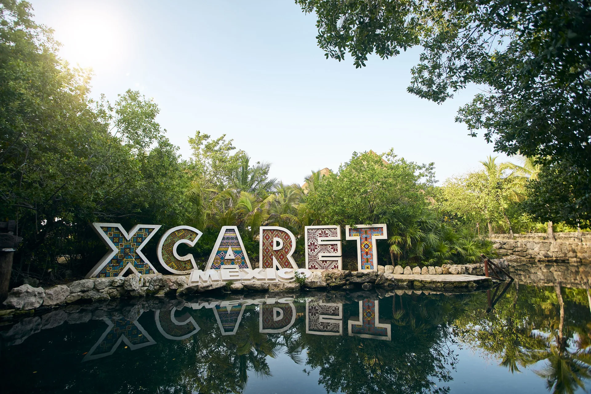 Colorful Hotel Xcaret Arte sign reflected in a lagoon at Hotel Xcaret Arte.