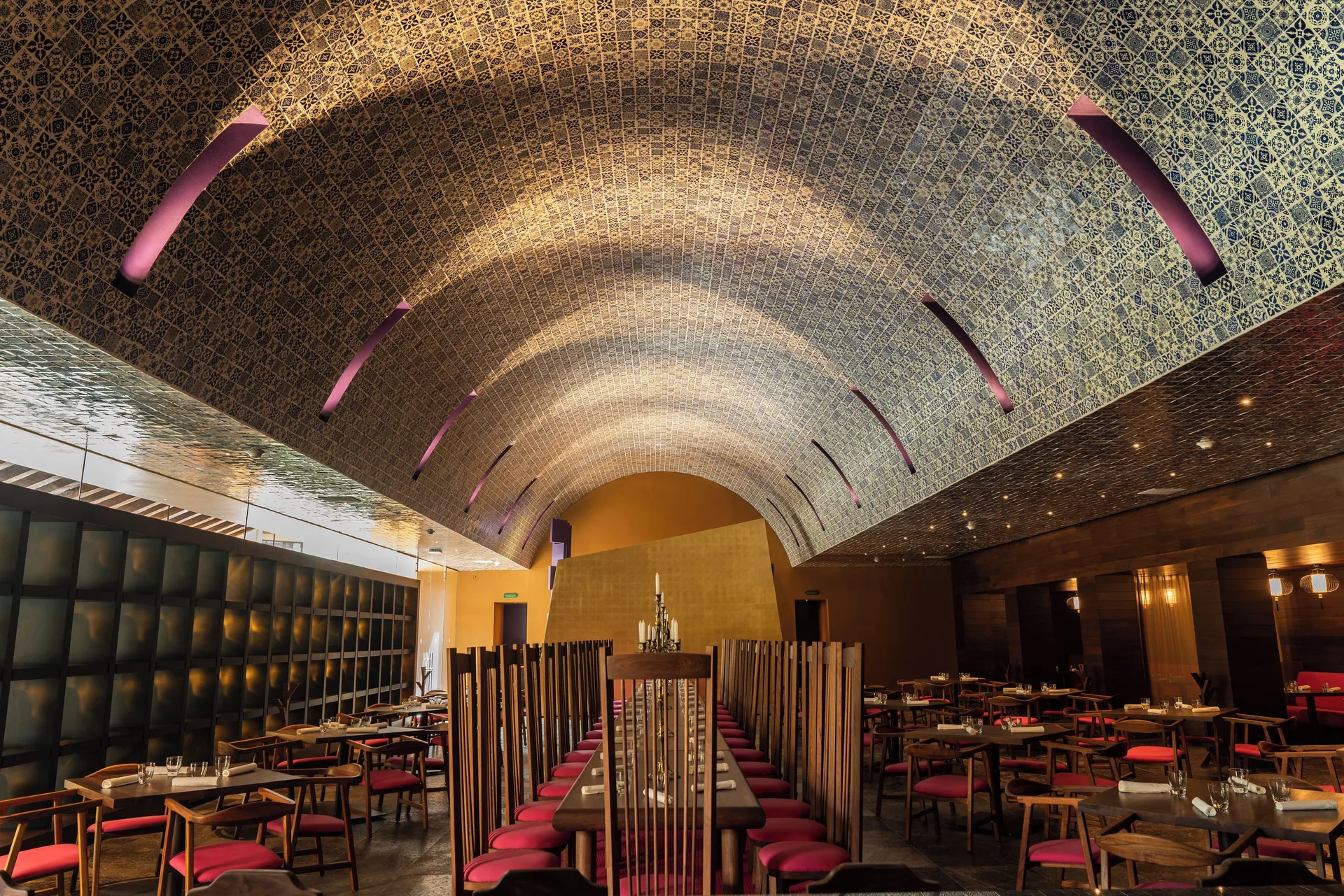Restaurant dining room with arched tiled ceiling and red chairs at Hotel Xcaret Arte.