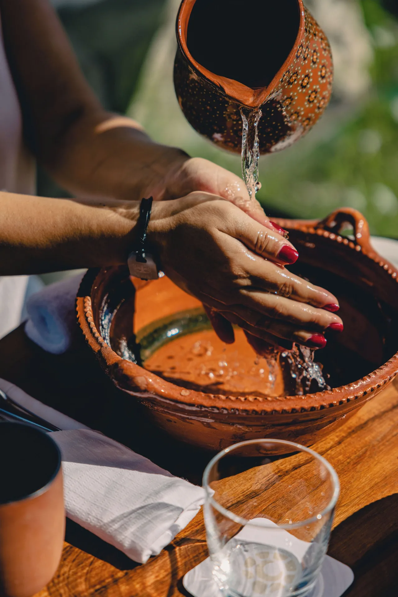 Water poured from a clay pitcher over hands at a table at Hotel Xcaret Arte.