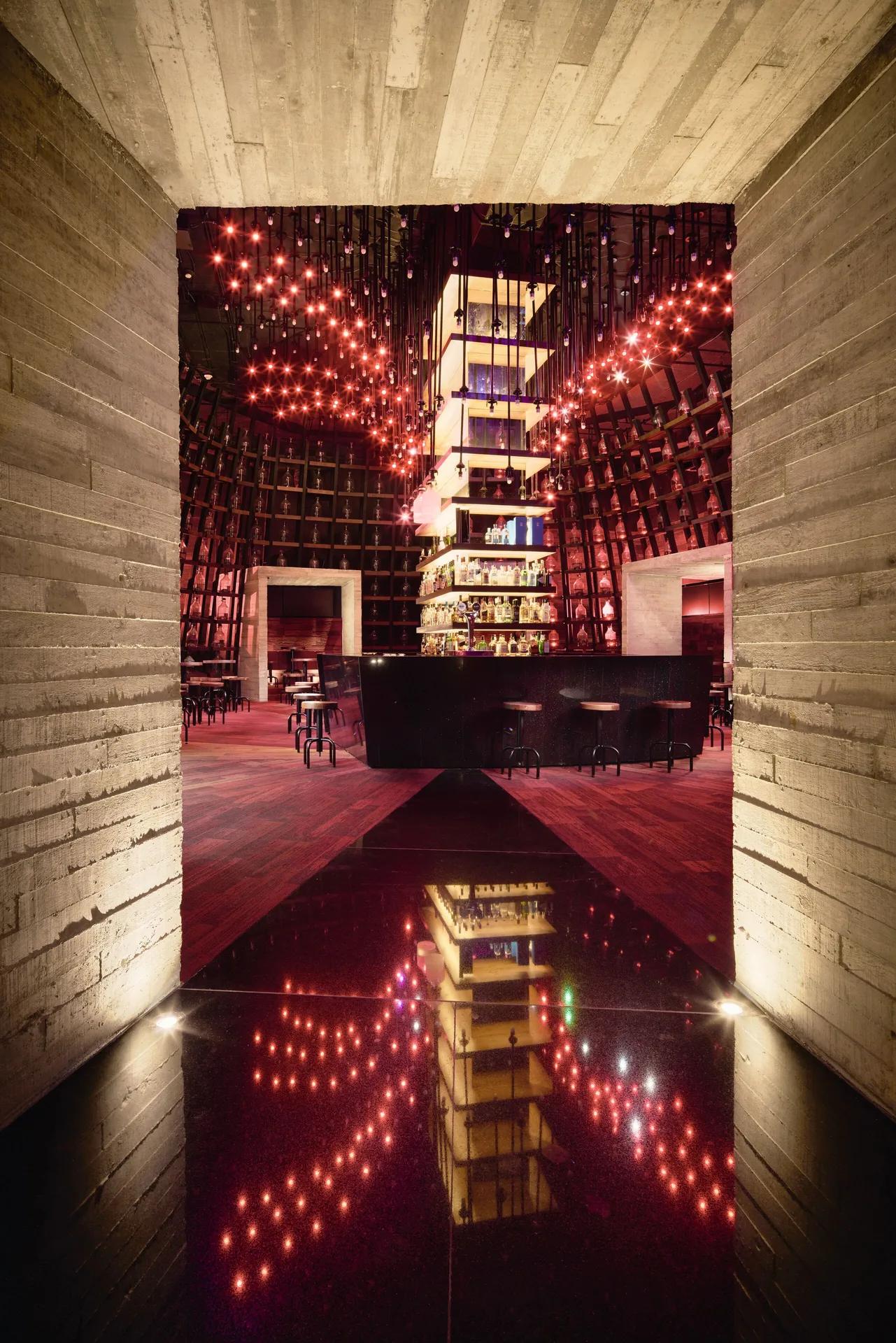 Dramatic dark bar with red lights and mirrored floor at Hotel Xcaret Arte.