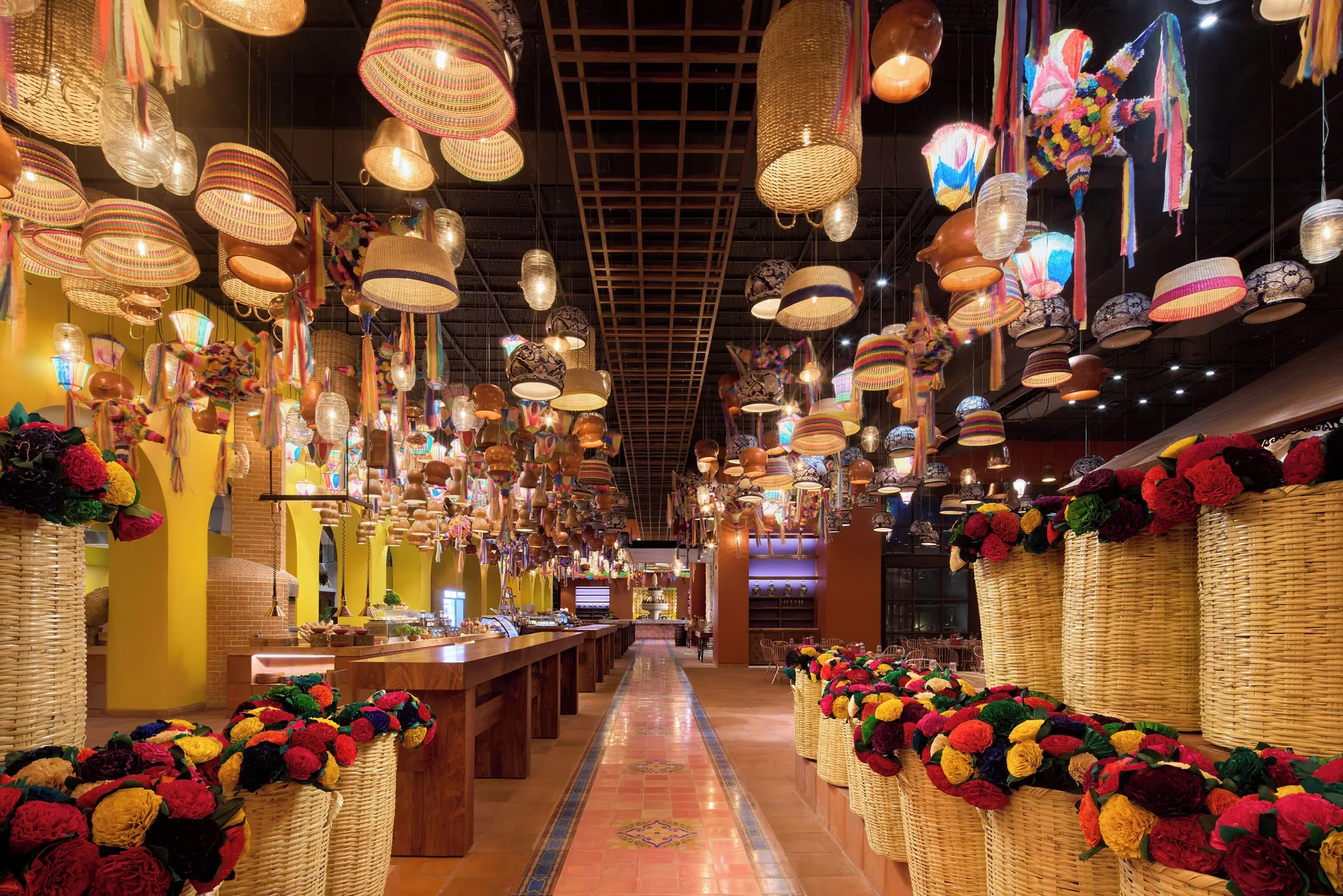 Colorful buffet restaurant interior with hanging baskets at Hotel Xcaret Arte.