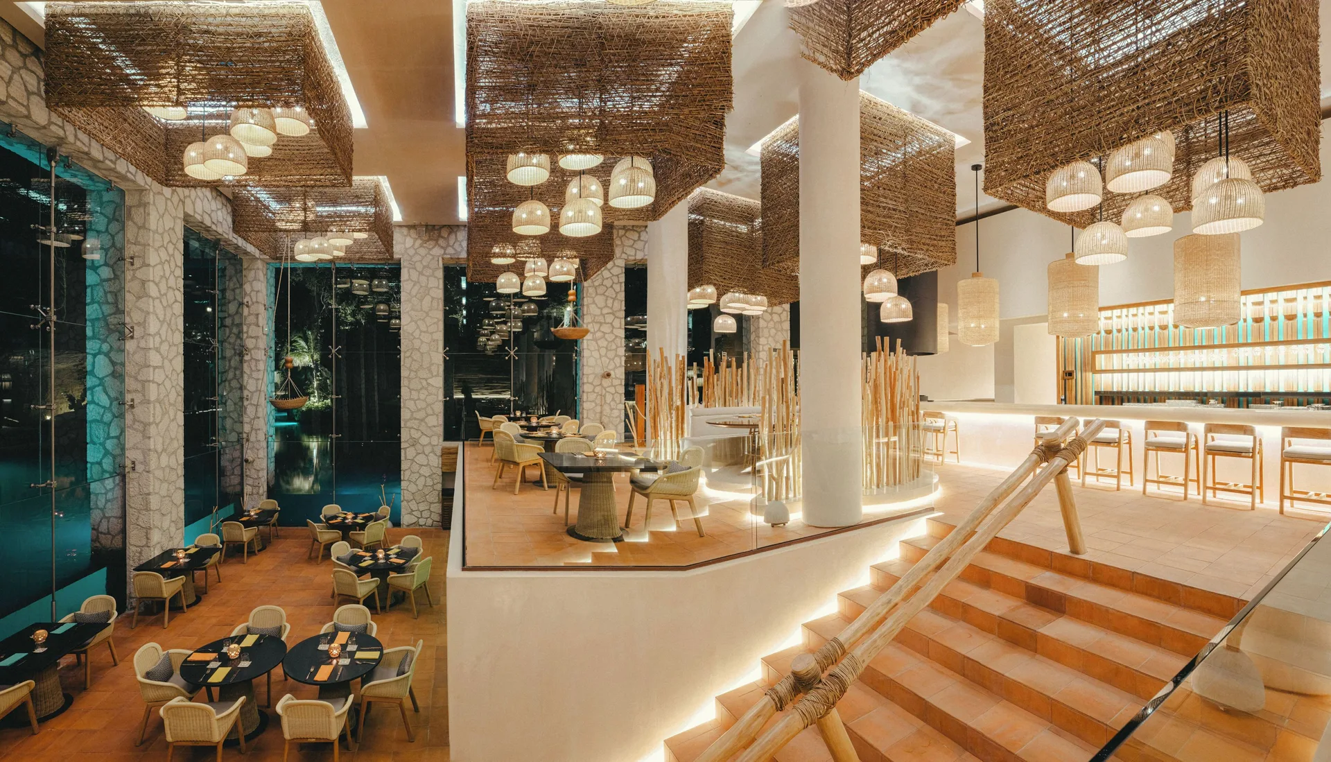 Multi-level restaurant with woven ceiling features and bar seating at Hotel Xcaret Arte.