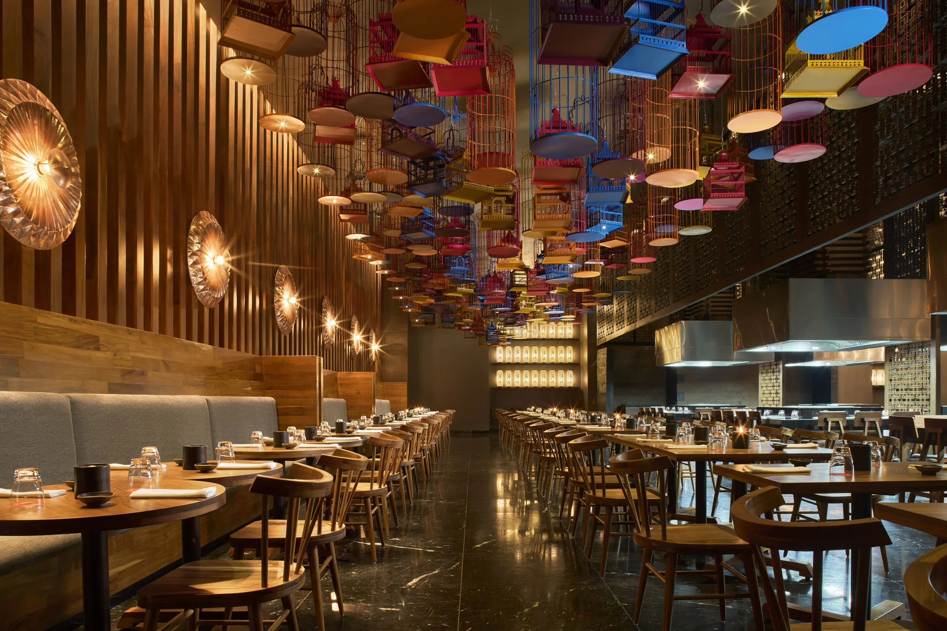 Long restaurant dining room with colorful birdcage ceiling decor at Hotel Xcaret Arte.