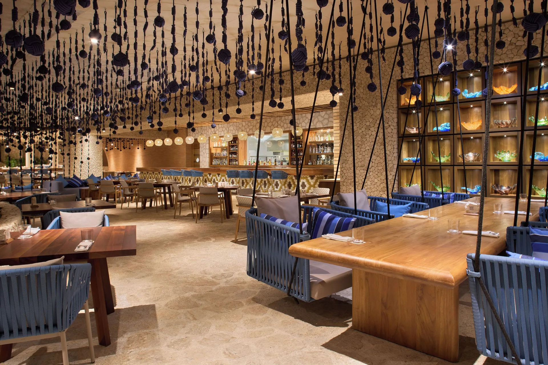 Restaurant dining room with hanging swing chairs at Hotel Xcaret Arte.