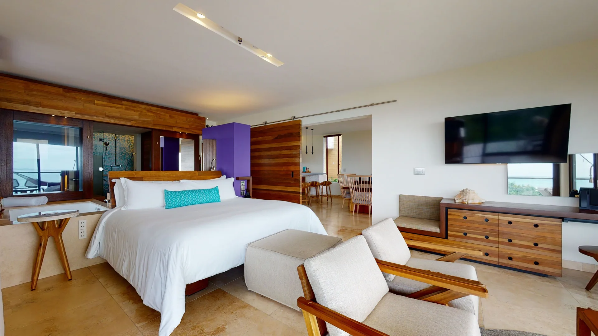 Oceanfront Junior Suite bedroom with king bed, sitting area and TV at Hotel Xcaret Arte.