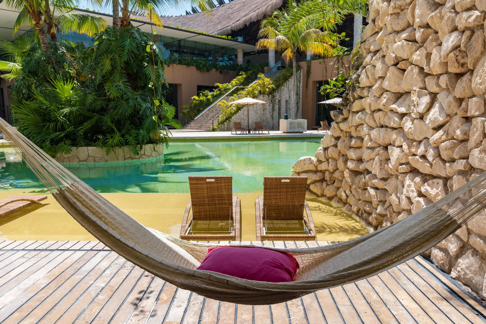 Swim-up room deck with hammock, loungers, and pool at Hotel Xcaret Arte.