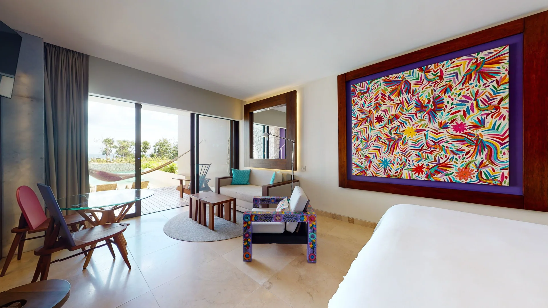 Oceanfront swim-up room with king bed, colorful wall art and terrace at Hotel Xcaret Arte.