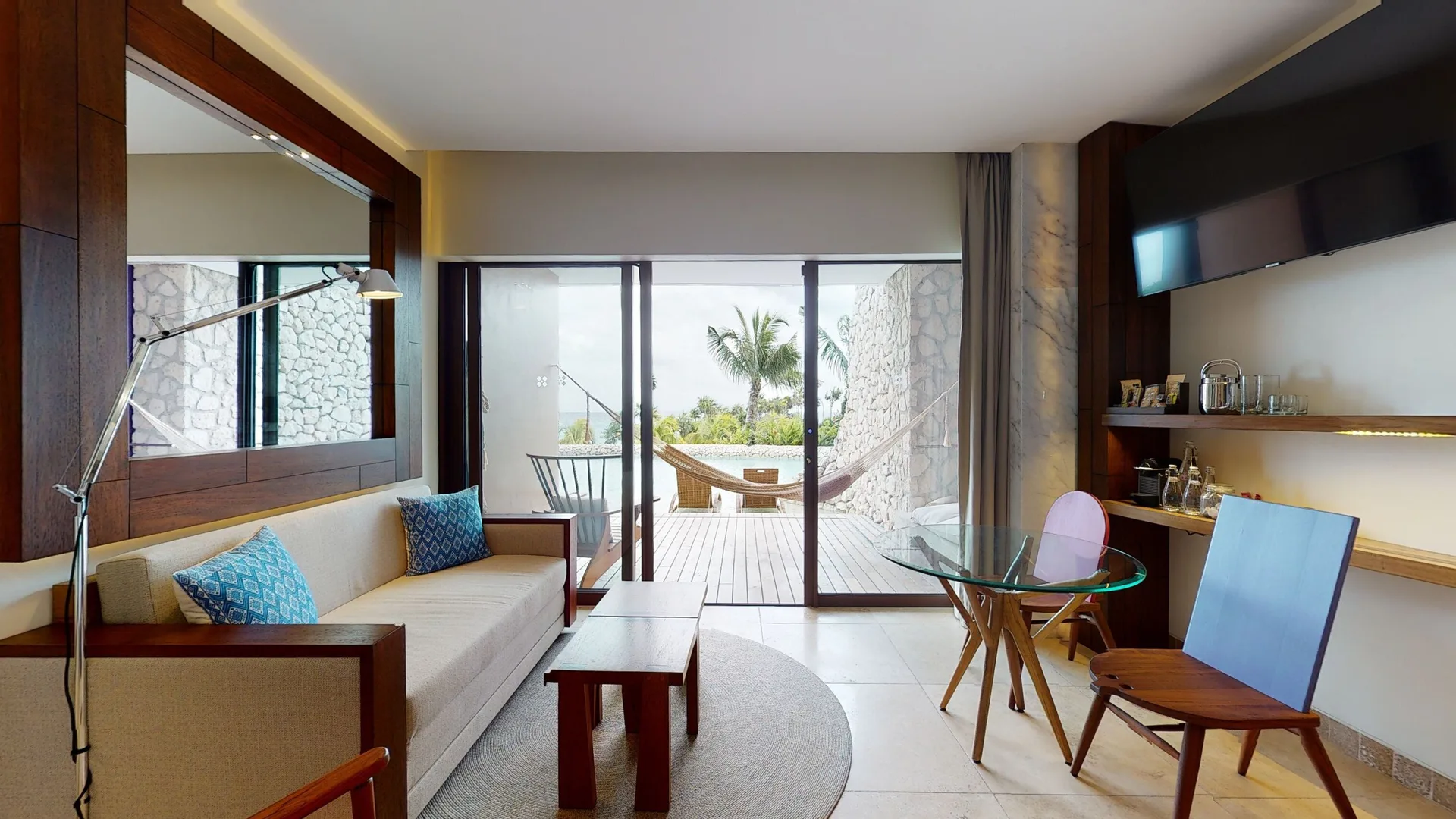Oceanfront room living area with sofa, dining table, and terrace at Hotel Xcaret Arte.