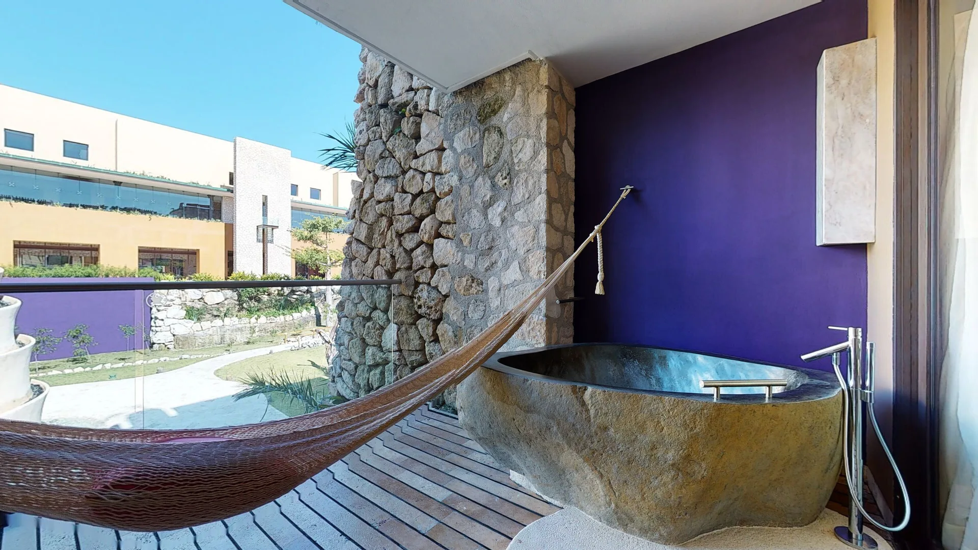 Garden Spa suite balcony at Hotel Xcaret Arte with hammock, stone soaking tub, and garden-facing railing.